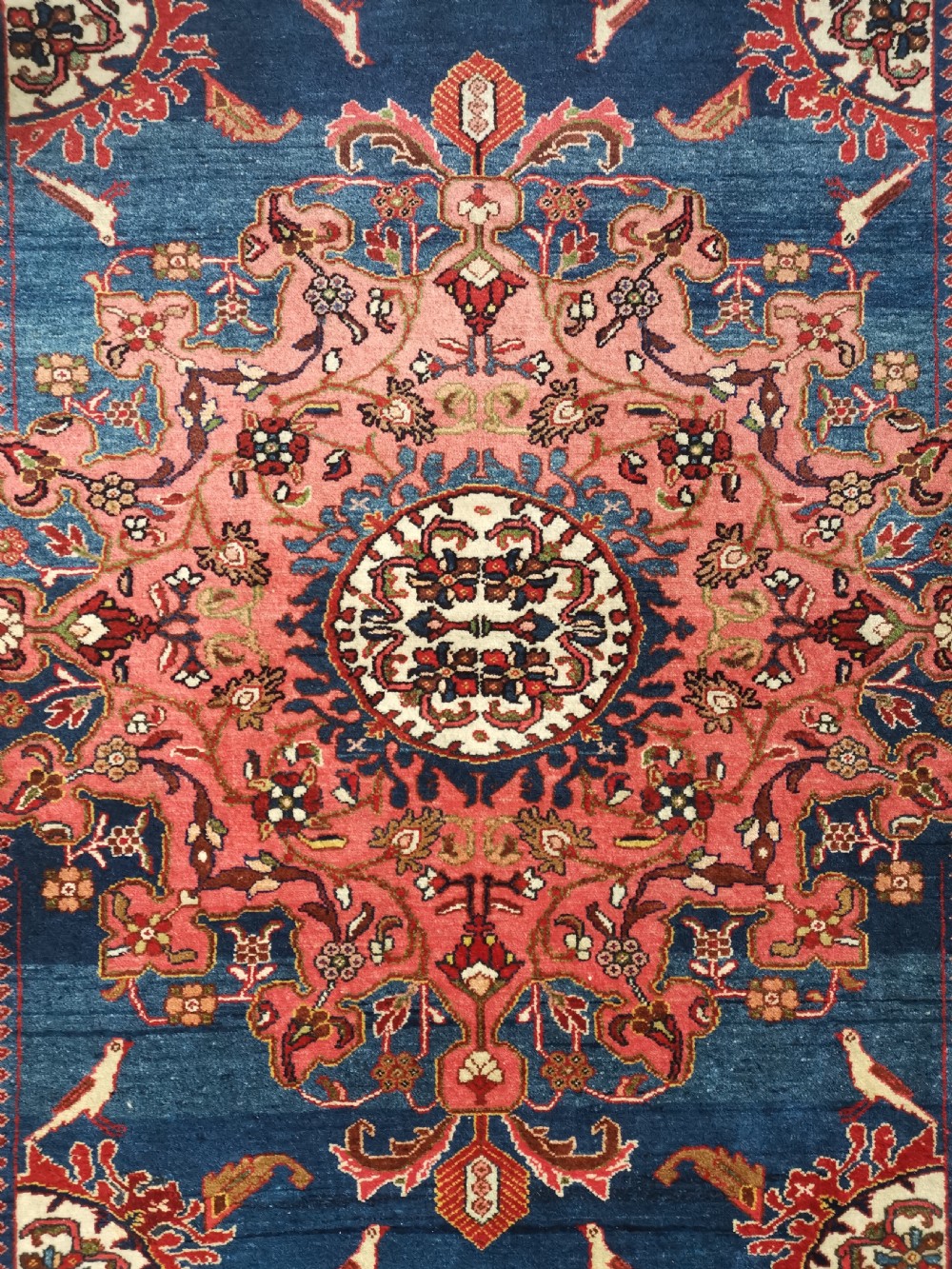 A hand-knotted antique Persian Tafresh wool rug featuring a deep navy blue field, a prominent rose pink central medallion, ornate floral spandrels, and bird motifs. View II