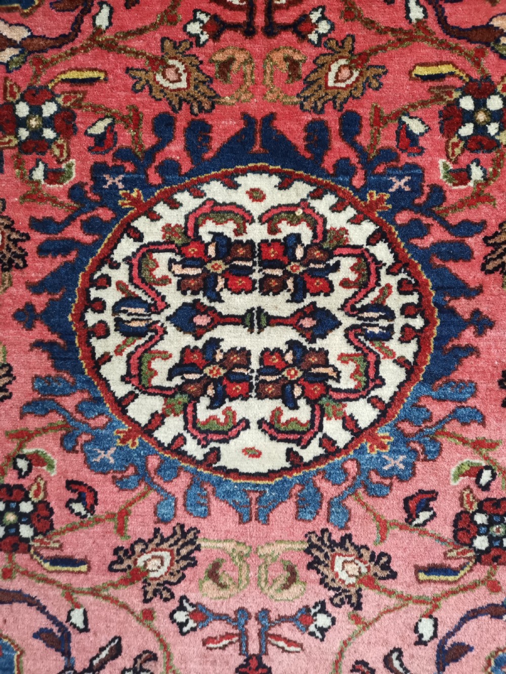 A hand-knotted antique Persian Tafresh wool rug featuring a deep navy blue field, a prominent rose pink central medallion, ornate floral spandrels, and bird motifs. View III