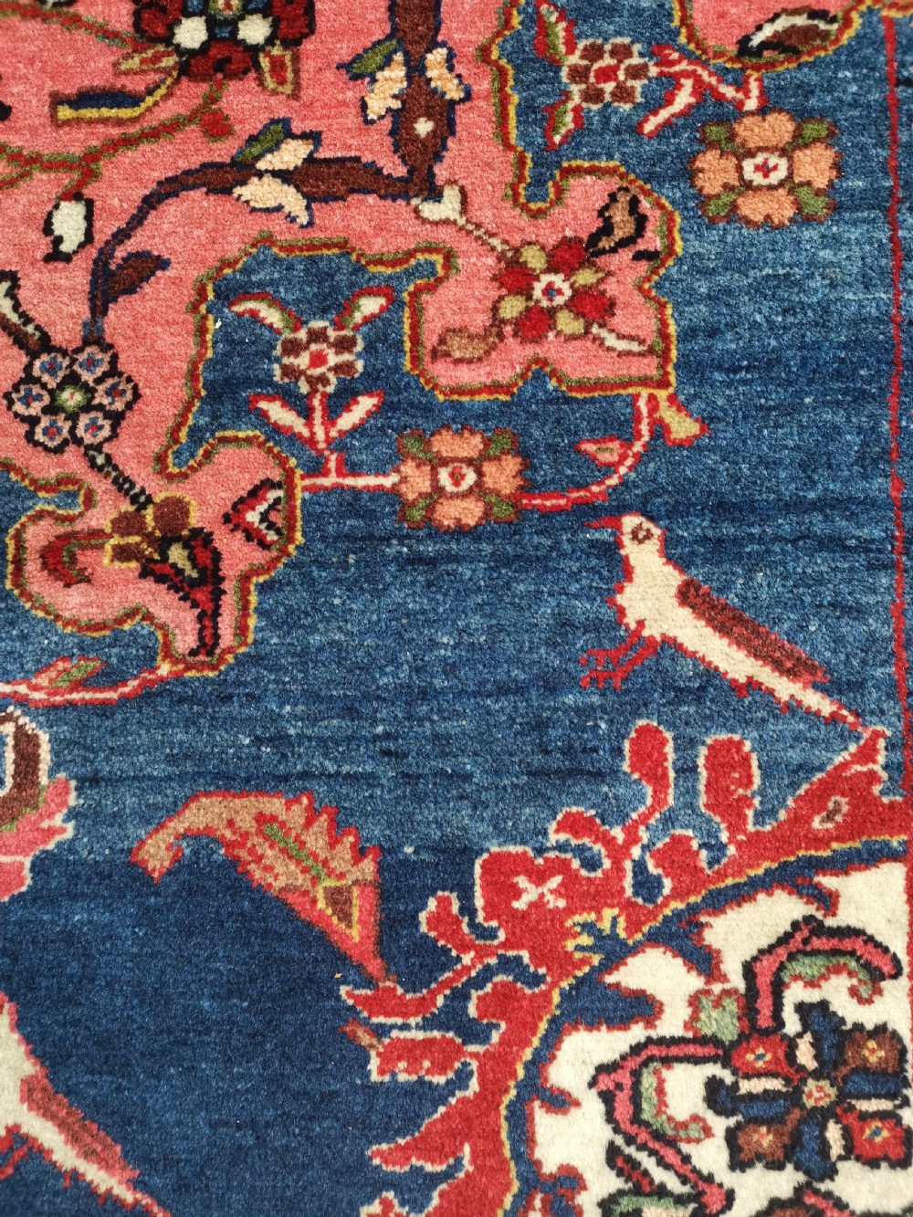 A hand-knotted antique Persian Tafresh wool rug featuring a deep navy blue field, a prominent rose pink central medallion, ornate floral spandrels, and bird motifs. View V