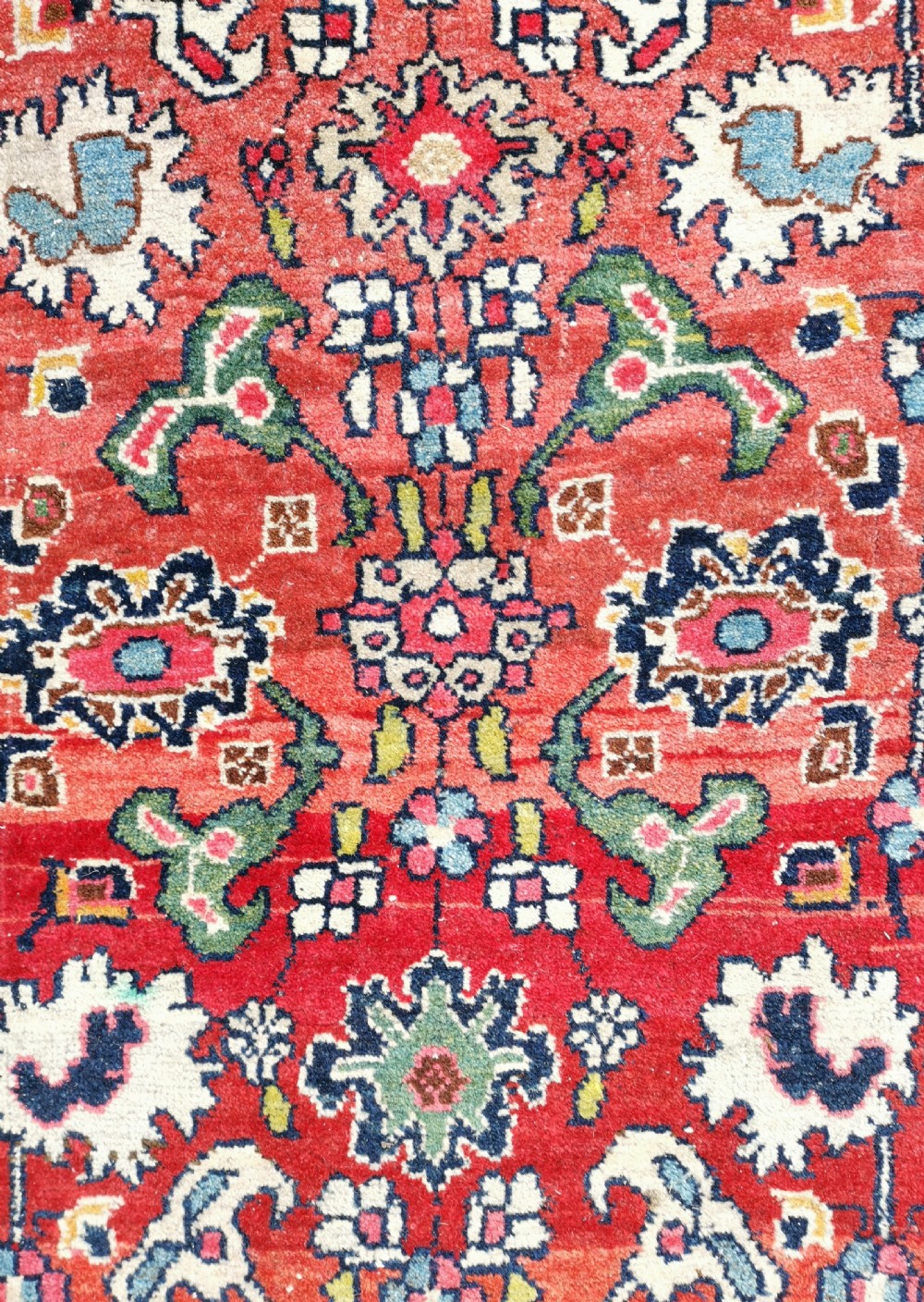 A rectangular hand-knotted Persian Bijar rug displaying a dense floral pattern across a red field bordered by navy blue decorative banding. View VI