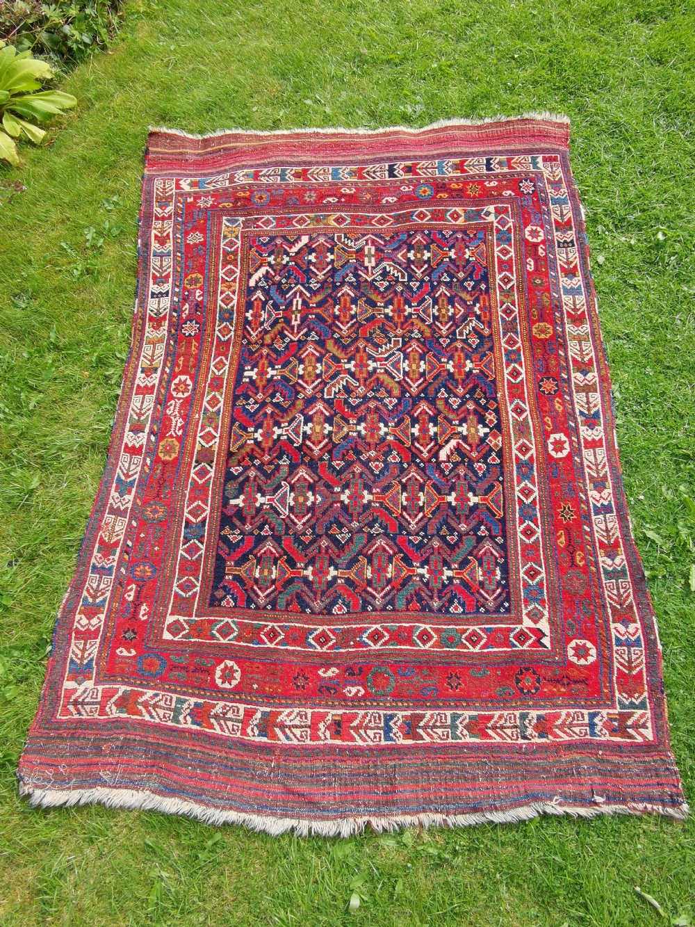 A hand-knotted antique Afshar wool rug featuring a geometric diamond lattice pattern in crimson red and navy blue with detailed borders.