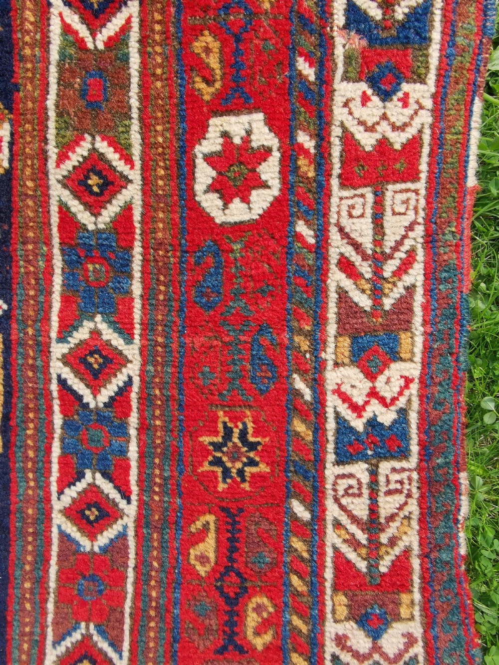 A hand-knotted antique Afshar wool rug featuring a geometric diamond lattice pattern in crimson red and navy blue with detailed borders. View II