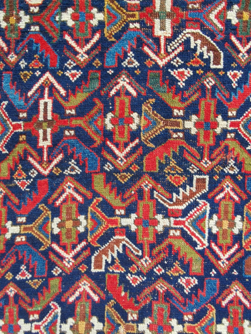 A hand-knotted antique Afshar wool rug featuring a geometric diamond lattice pattern in crimson red and navy blue with detailed borders. View V