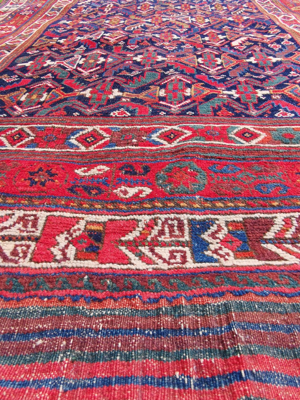 A hand-knotted antique Afshar wool rug featuring a geometric diamond lattice pattern in crimson red and navy blue with detailed borders. View VII
