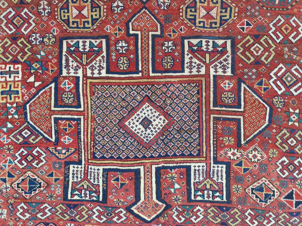 A handwoven rectangular Quchan Kurdish wool rug featuring geometric stepped medallions and repeating motifs in shades of terracotta red, navy blue, and cream. View VIII