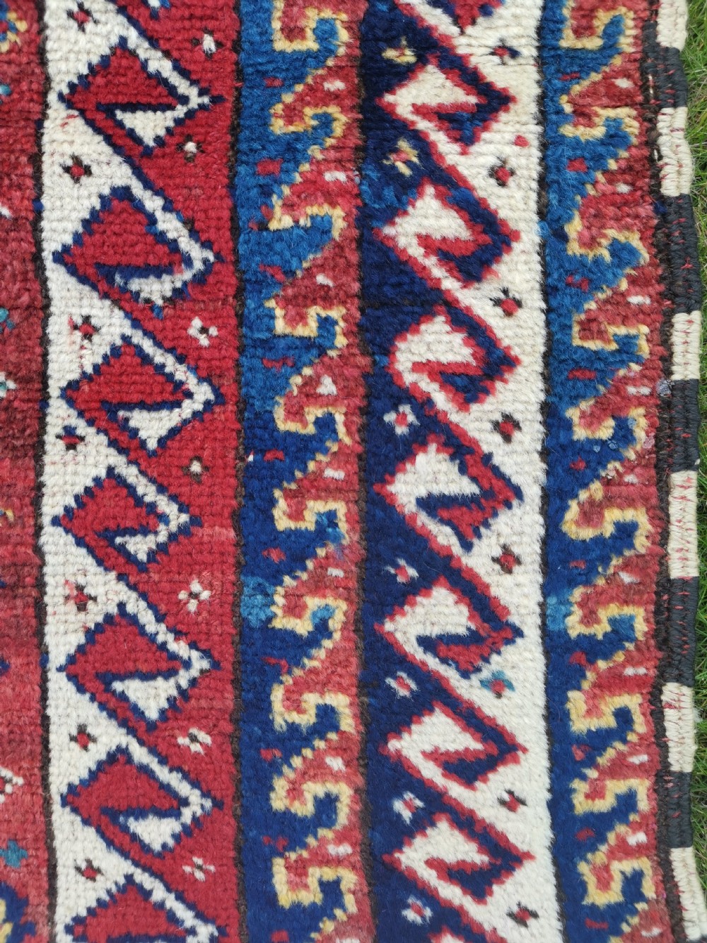 A handwoven rectangular Quchan Kurdish wool rug featuring geometric stepped medallions and repeating motifs in shades of terracotta red, navy blue, and cream. View XI