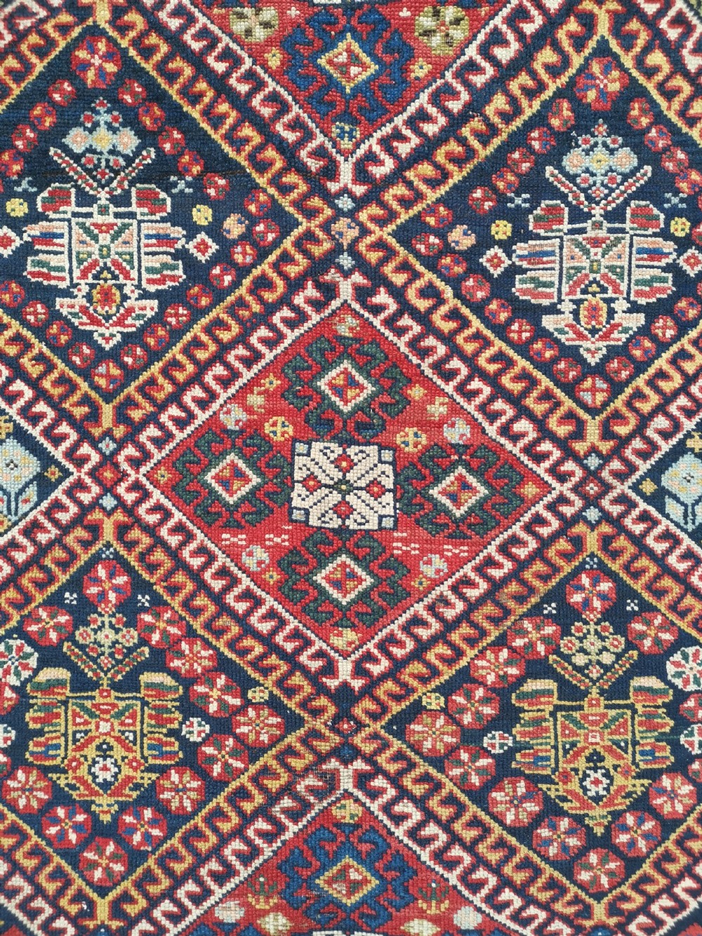 An antique Persian Luri hand-knotted wool runner featuring central diamond medallions in red and navy blue framed by geometric borders. View II