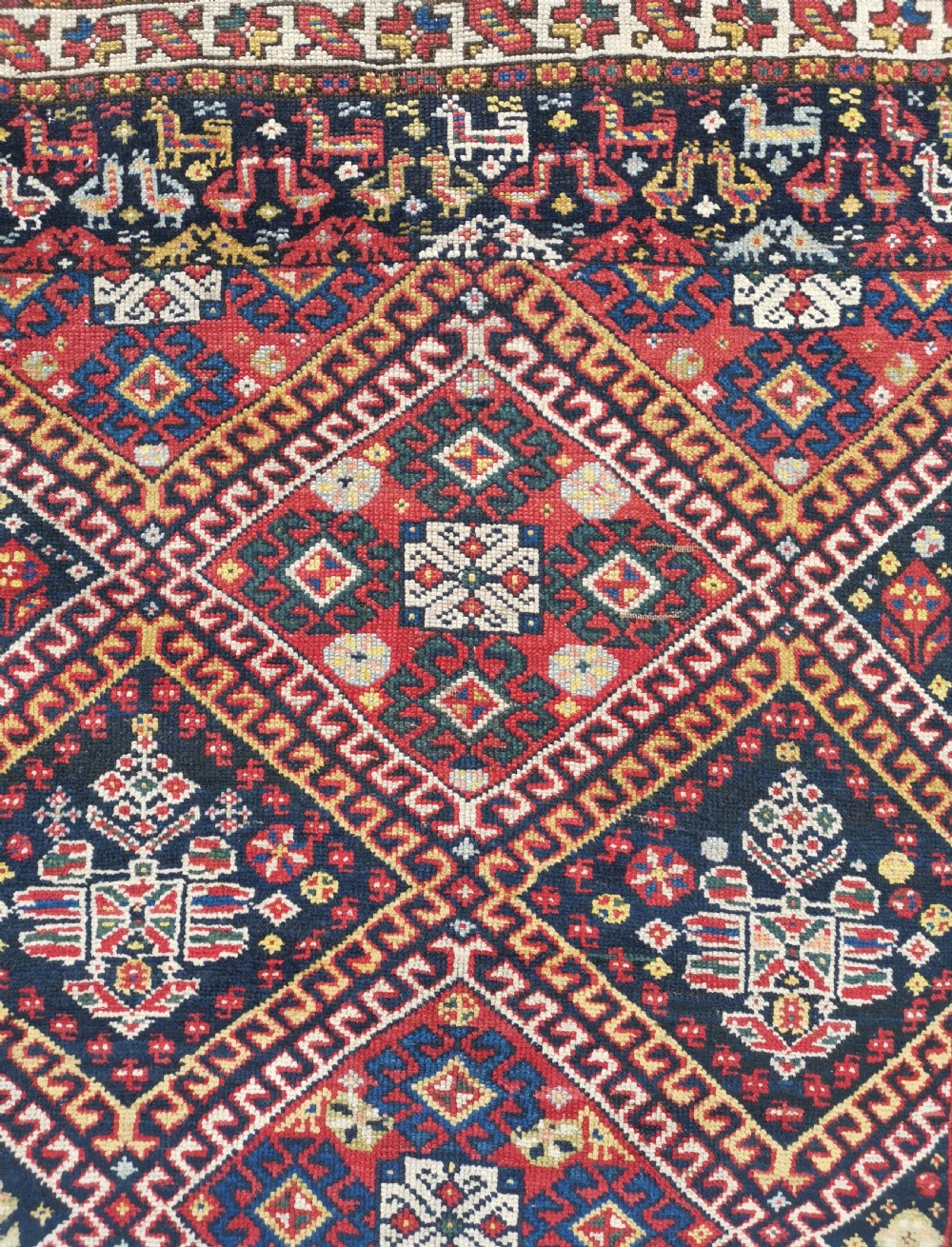An antique Persian Luri hand-knotted wool runner featuring central diamond medallions in red and navy blue framed by geometric borders. View IV