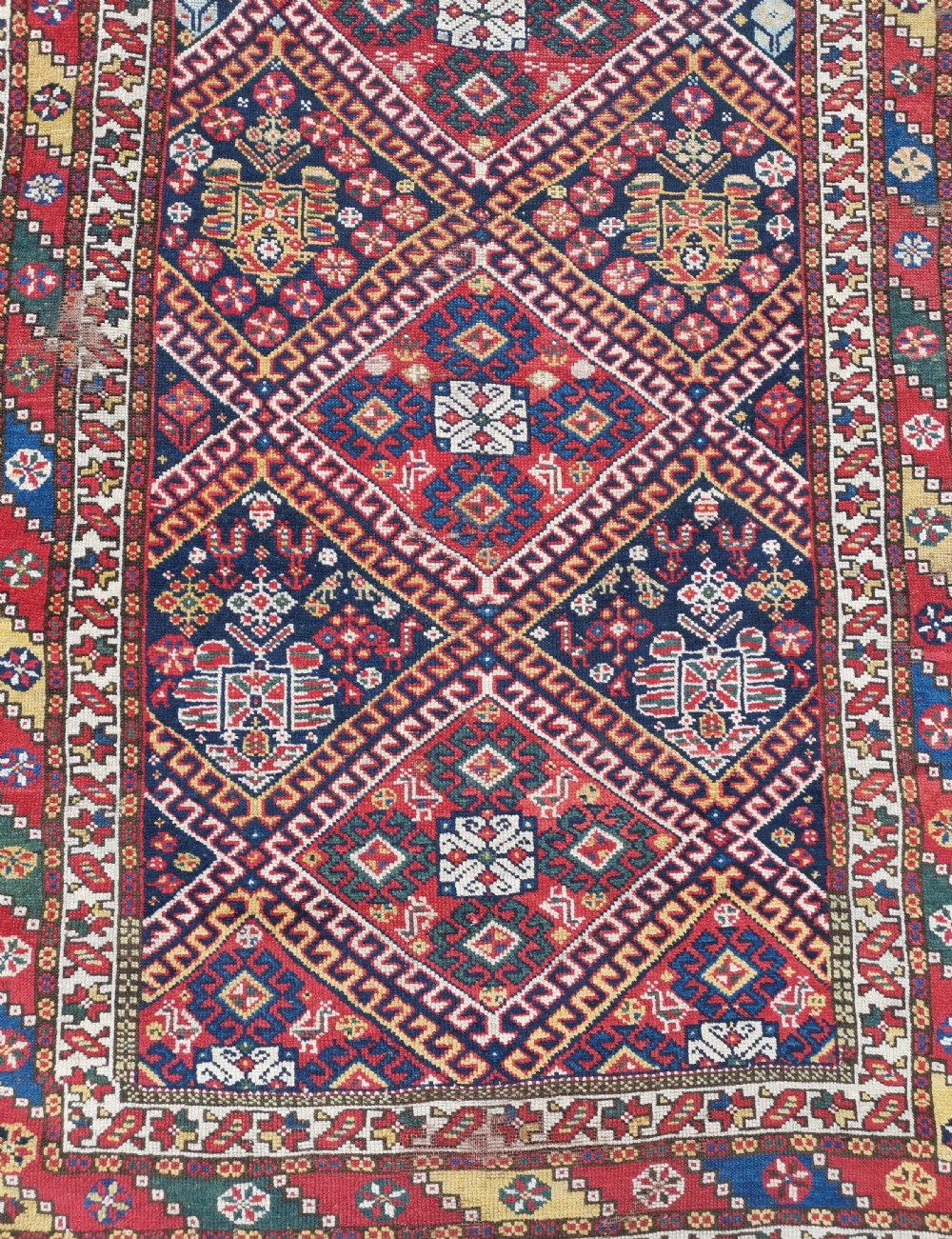 An antique Persian Luri hand-knotted wool runner featuring central diamond medallions in red and navy blue framed by geometric borders. View V