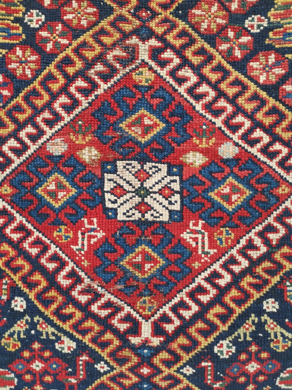 An antique Persian Luri hand-knotted wool runner featuring central diamond medallions in red and navy blue framed by geometric borders. View VII