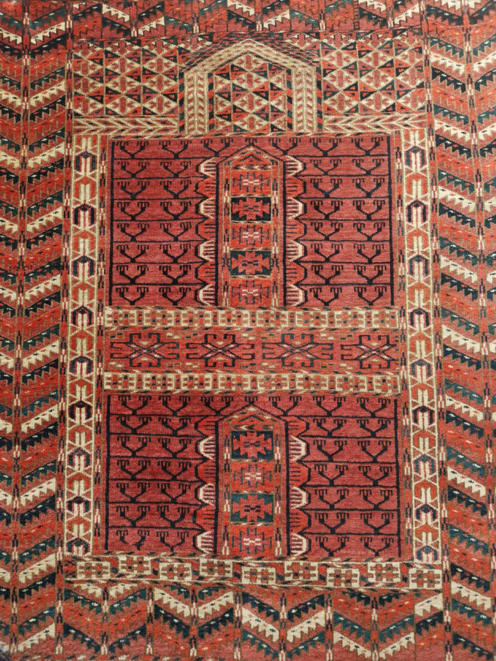 An antique hand-knotted Tekke Turkmen engsi wool rug featuring a red four-panel hatchli design with geometric tribal borders. View II