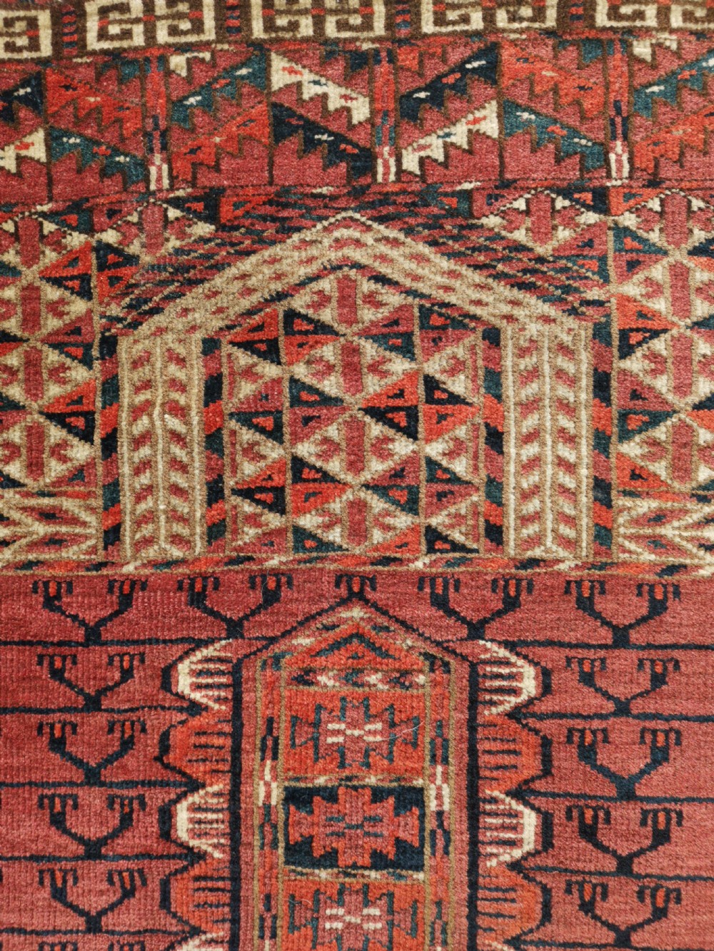 An antique hand-knotted Tekke Turkmen engsi wool rug featuring a red four-panel hatchli design with geometric tribal borders. View III