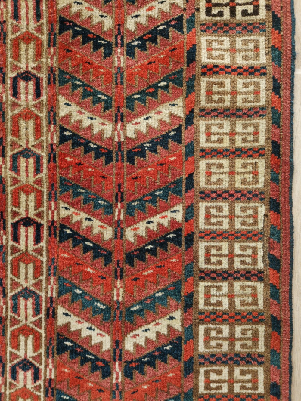 An antique hand-knotted Tekke Turkmen engsi wool rug featuring a red four-panel hatchli design with geometric tribal borders. View V