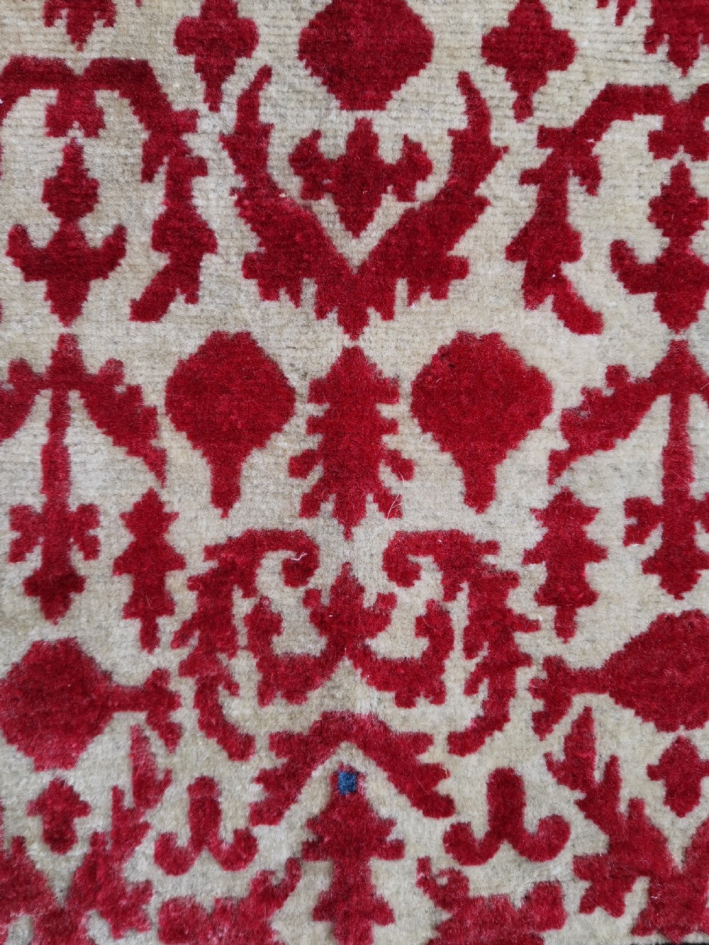 A hand-knotted rectangular antique Sarouk wool rug featuring a crimson red repeating floral pattern on a cream ground framed by a dark floral border. View IV