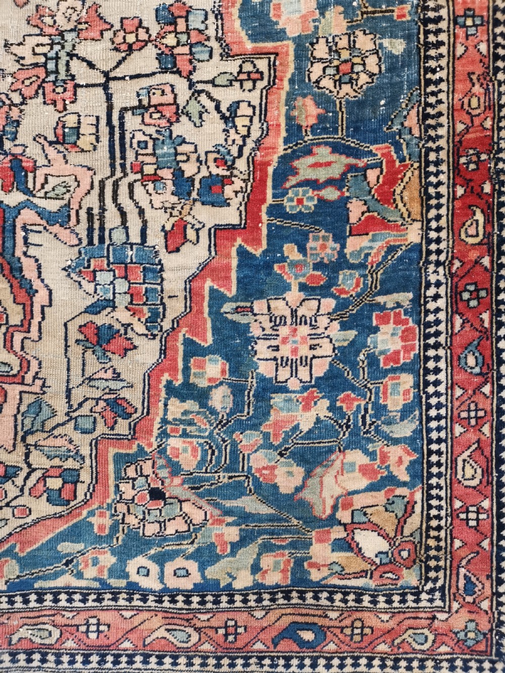 An antique hand-knotted Kashan Persian rug featuring a central blue medallion on a cream field with detailed floral borders. View V