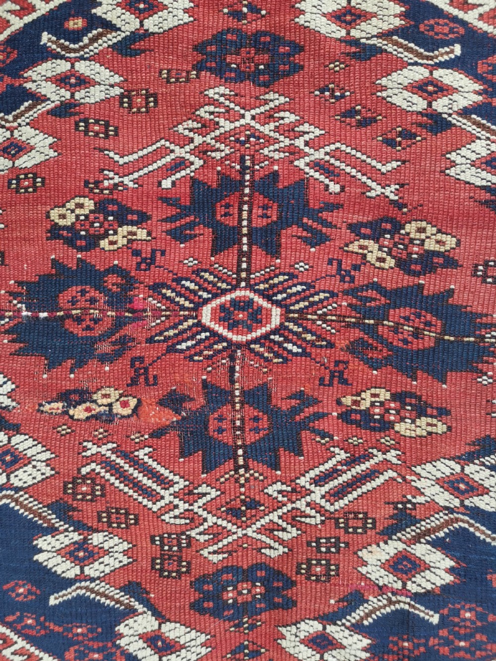 An antique square Anatolian Bergama wool rug featuring a central diamond medallion and geometric motifs in red, navy blue, and cream. View III