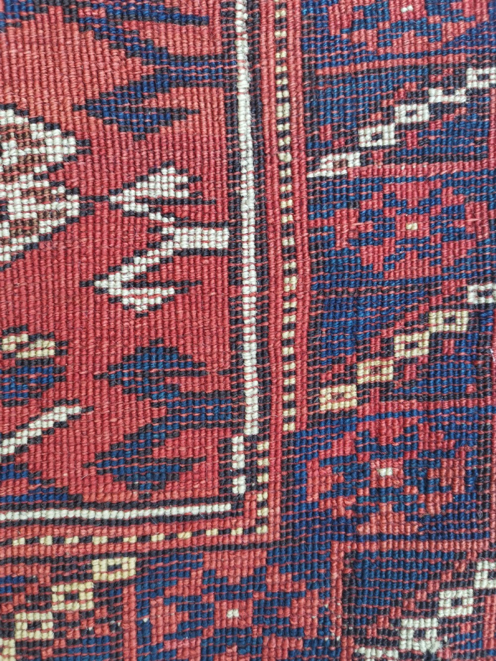An antique square Anatolian Bergama wool rug featuring a central diamond medallion and geometric motifs in red, navy blue, and cream. View V