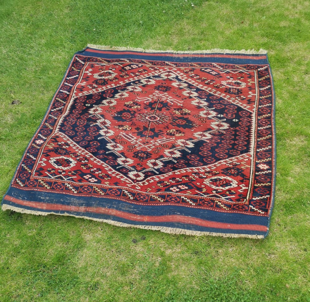An antique square Anatolian Bergama wool rug featuring a central diamond medallion and geometric motifs in red, navy blue, and cream. View VIII