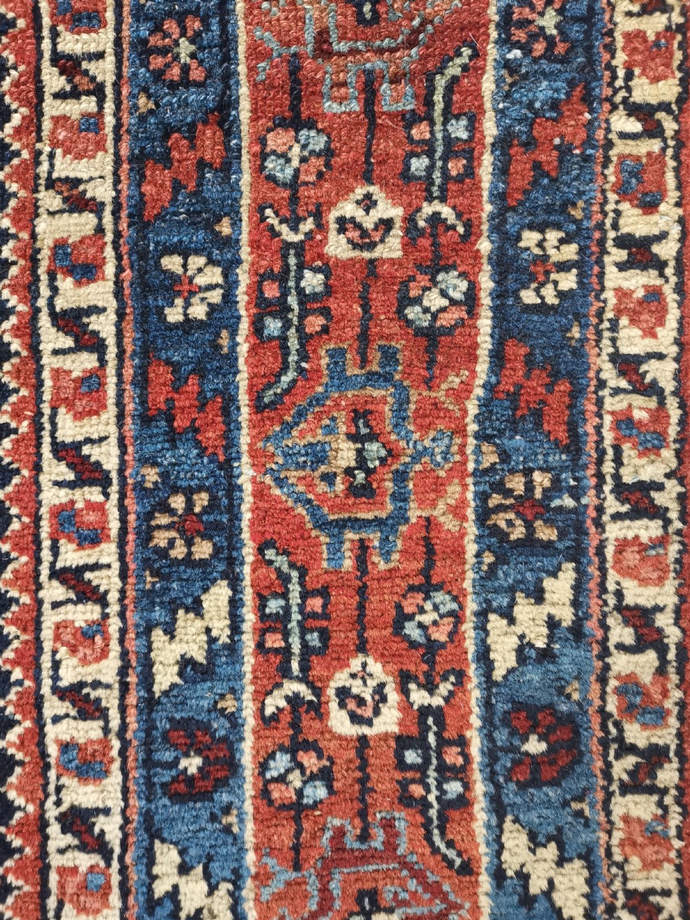 A hand-knotted antique Persian Hamadan wool rug featuring a navy blue field with geometric repeats framed by a terracotta spandrel and detailed multi-band border. View V