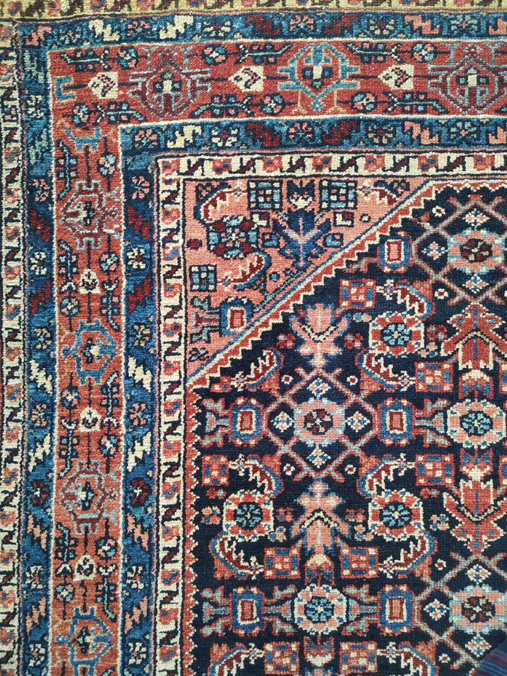 A hand-knotted antique Persian Hamadan wool rug featuring a navy blue field with geometric repeats framed by a terracotta spandrel and detailed multi-band border. View VIII