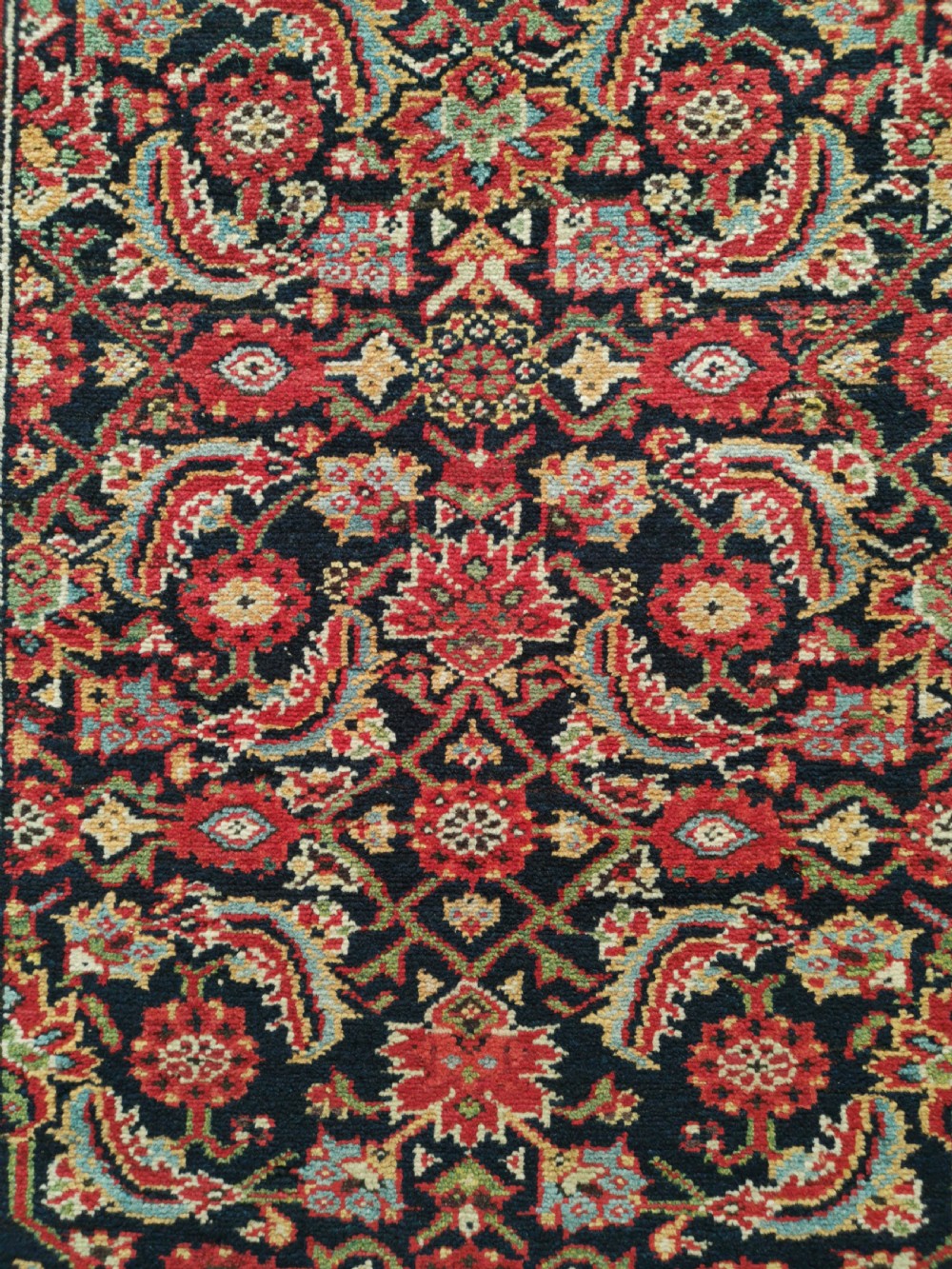 A rectangular hand-knotted antique Persian Fereghan wool rug featuring a dark navy central field with dense floral Herati patterns, framed by a red and blue multi-band border. View II