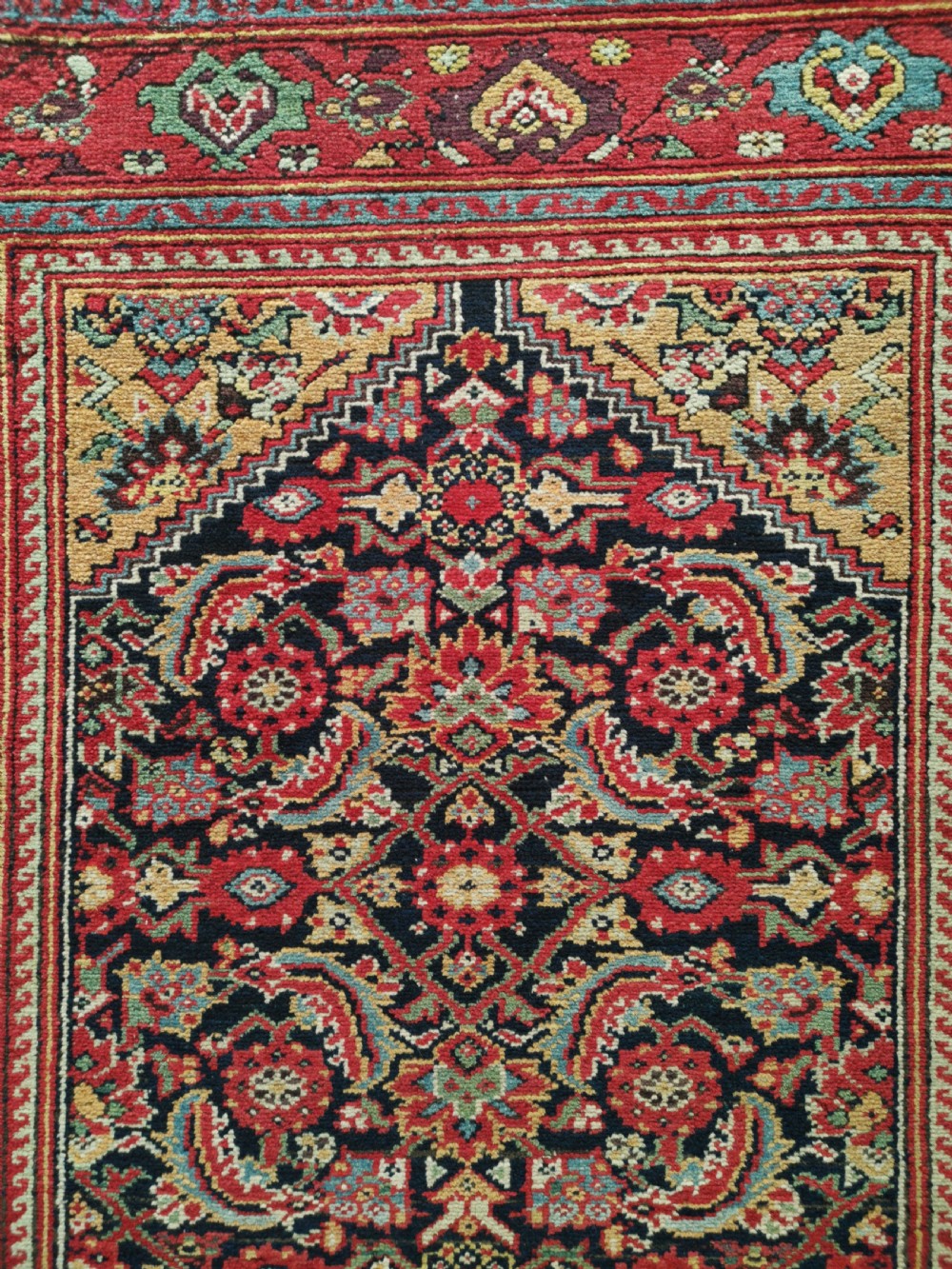 A rectangular hand-knotted antique Persian Fereghan wool rug featuring a dark navy central field with dense floral Herati patterns, framed by a red and blue multi-band border. View III