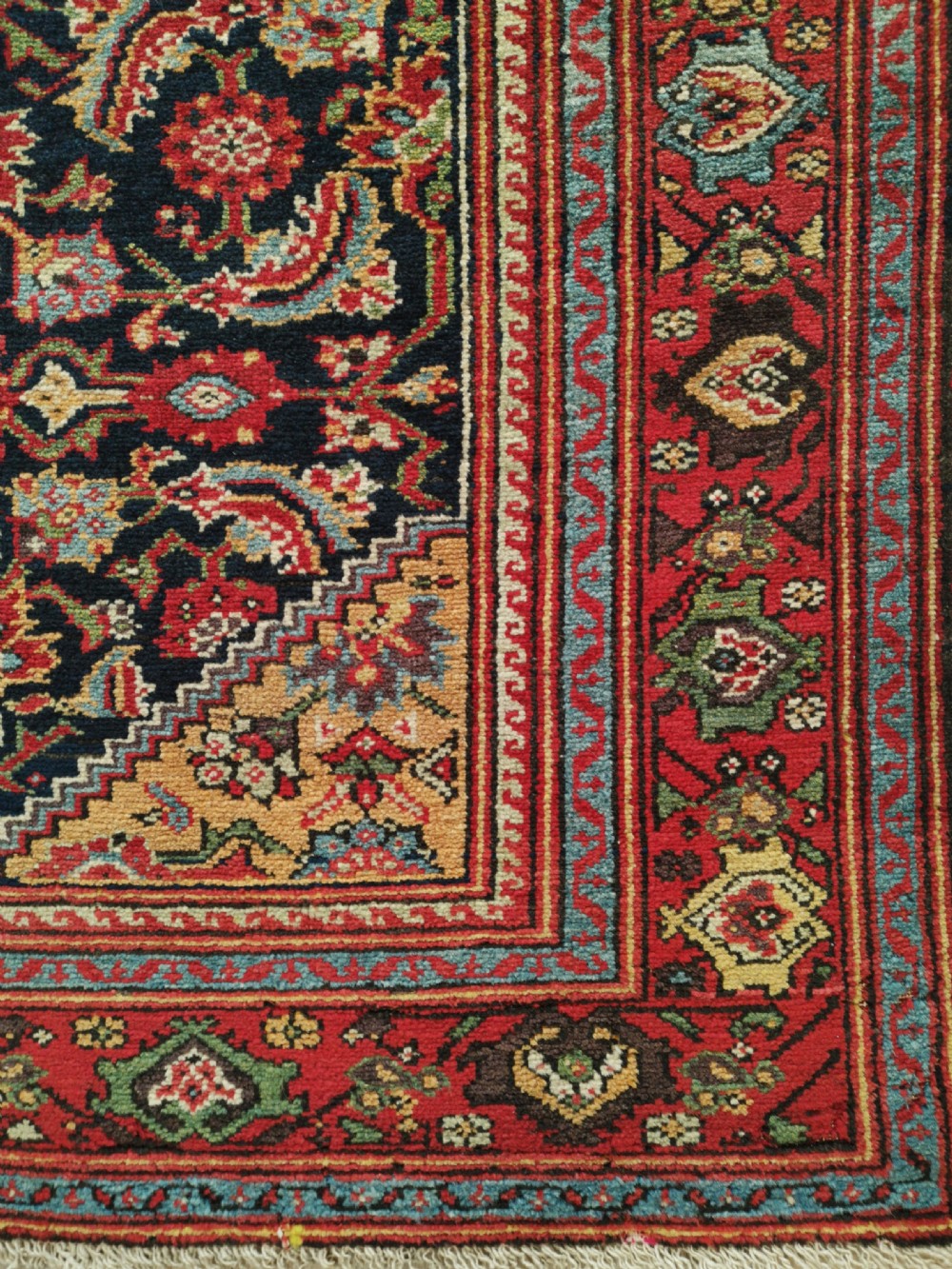 A rectangular hand-knotted antique Persian Fereghan wool rug featuring a dark navy central field with dense floral Herati patterns, framed by a red and blue multi-band border. View IV