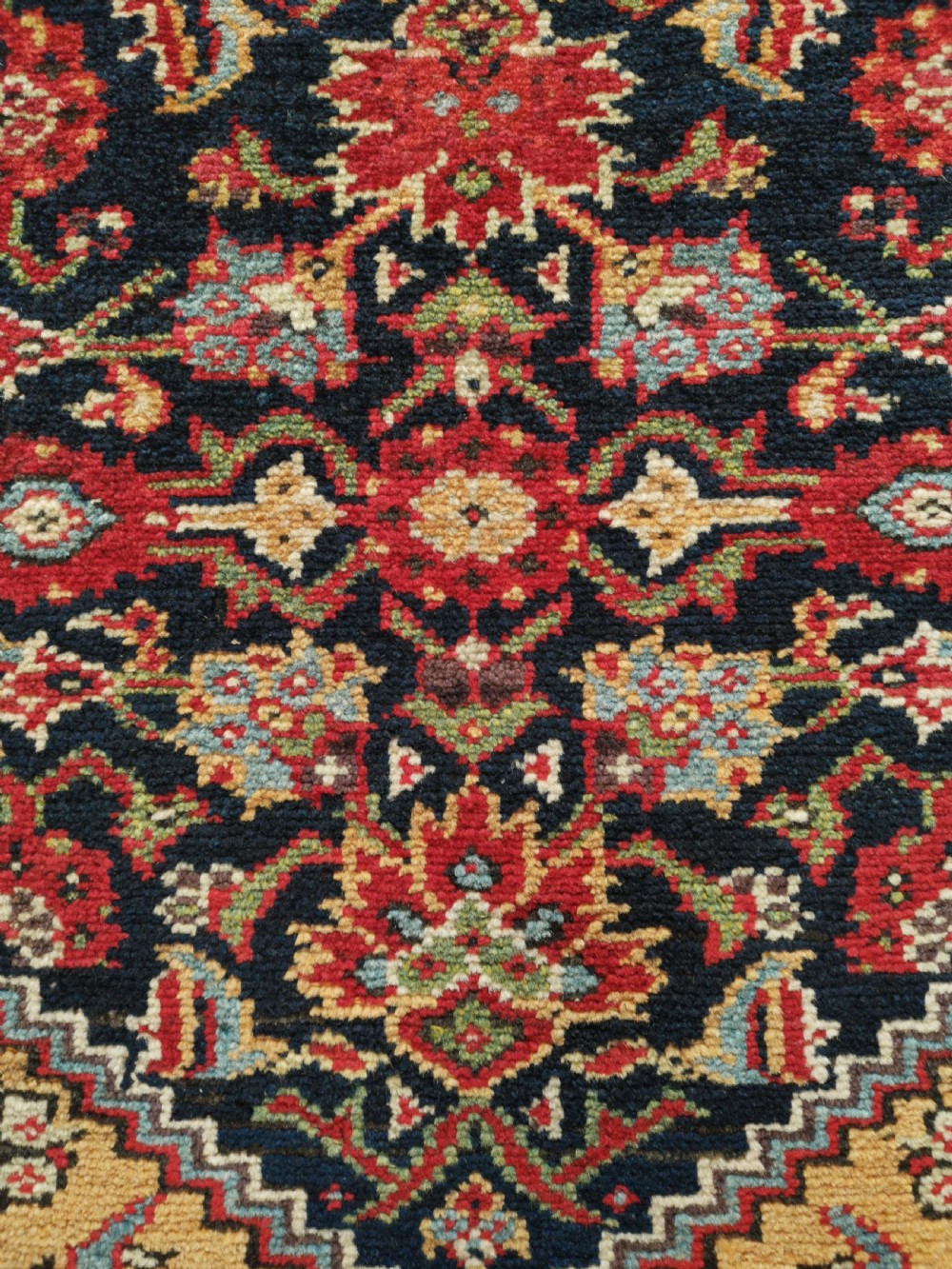A rectangular hand-knotted antique Persian Fereghan wool rug featuring a dark navy central field with dense floral Herati patterns, framed by a red and blue multi-band border. View VI