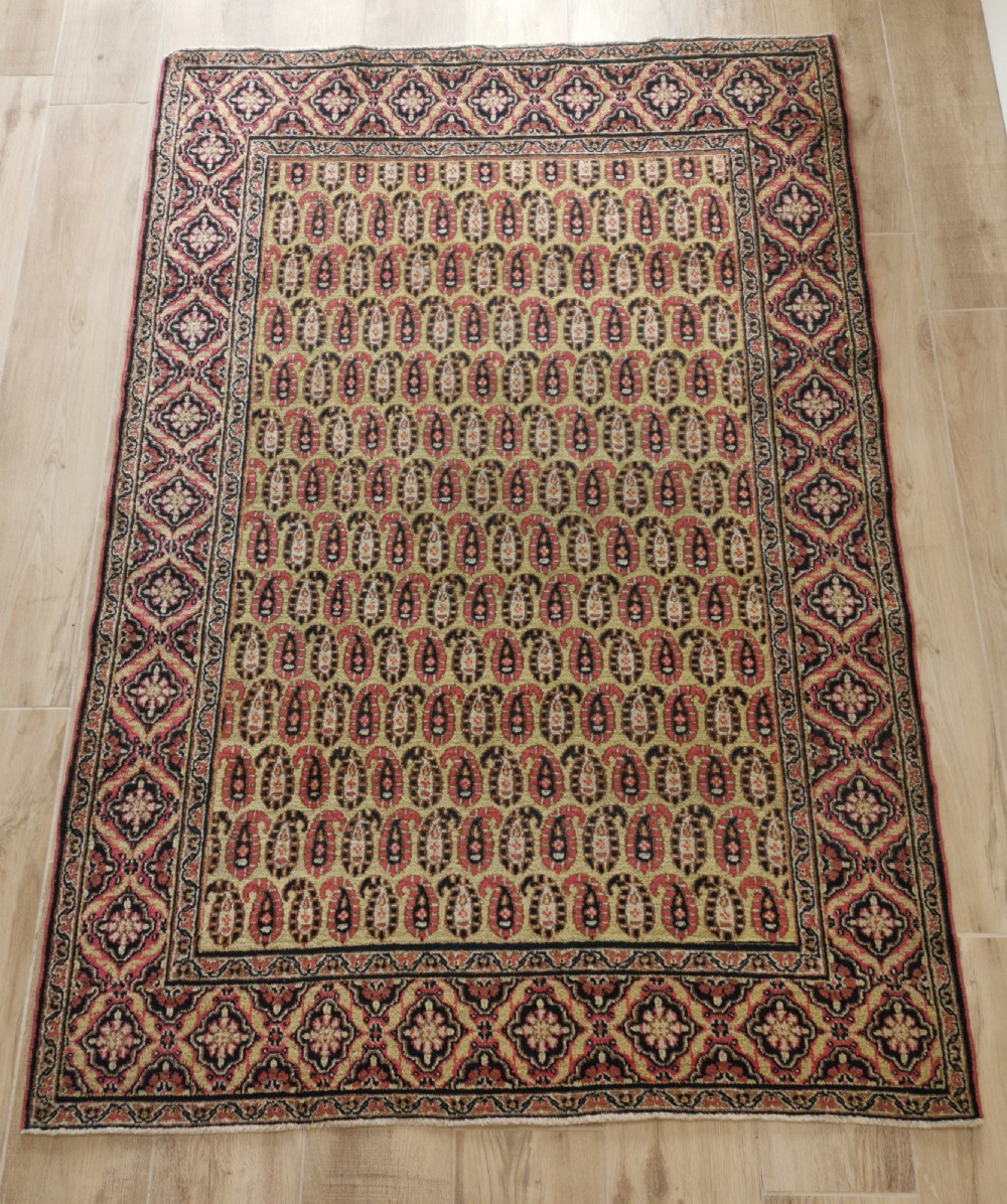 A rectangular hand-knotted Khorassan rug featuring a repeating red boteh pattern on a light yellow field, bordered by a dark floral rosette frame.