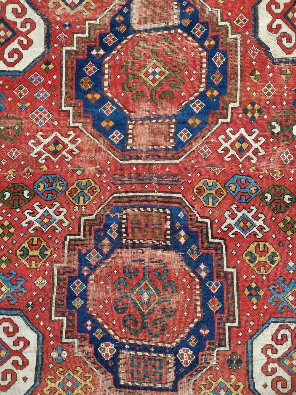 An antique Caucasian Lori Pambak hand-knotted wool rug featuring large octagonal medallions on a bold red field with geometric borders. View III