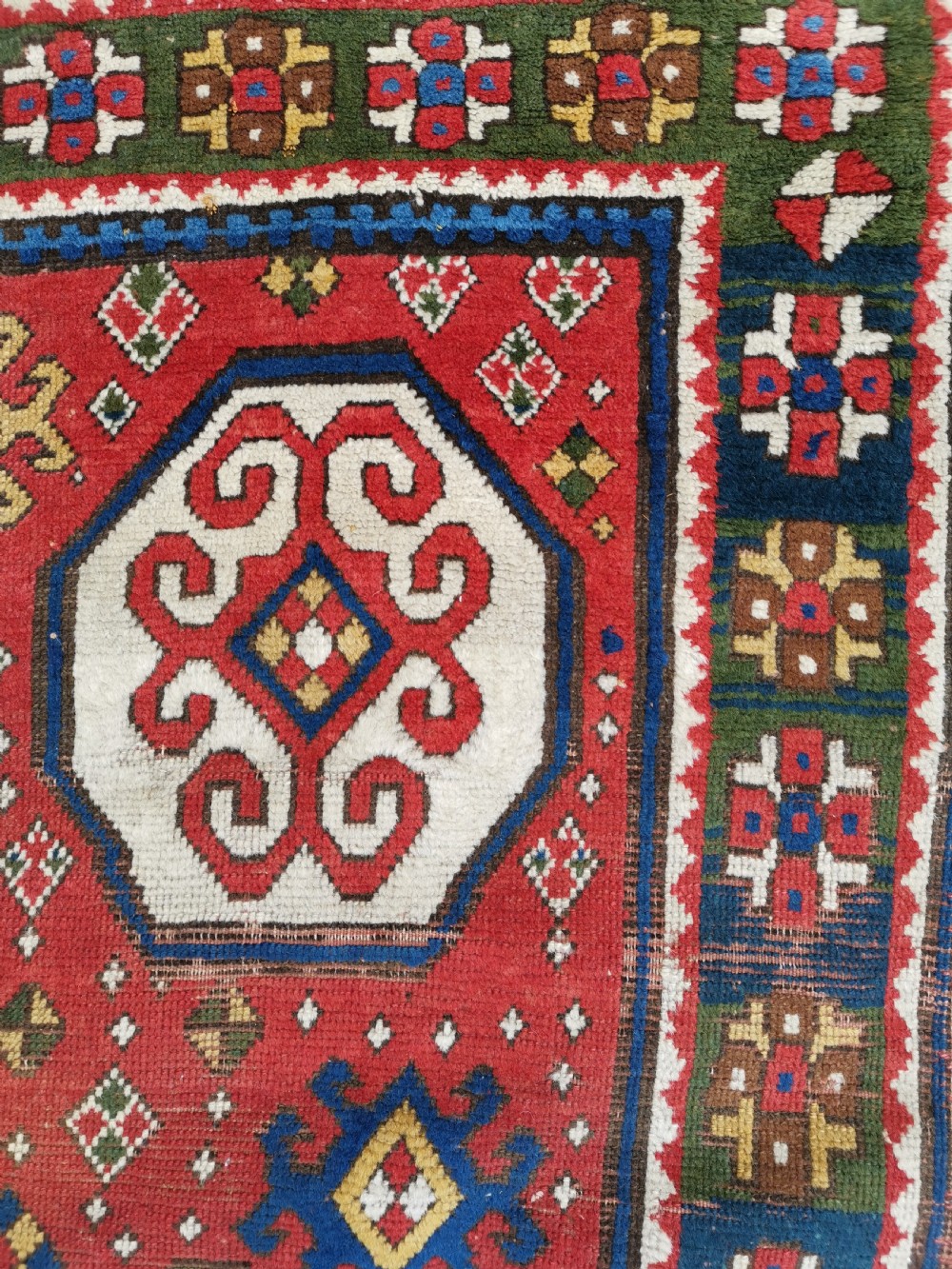 An antique Caucasian Lori Pambak hand-knotted wool rug featuring large octagonal medallions on a bold red field with geometric borders. View V