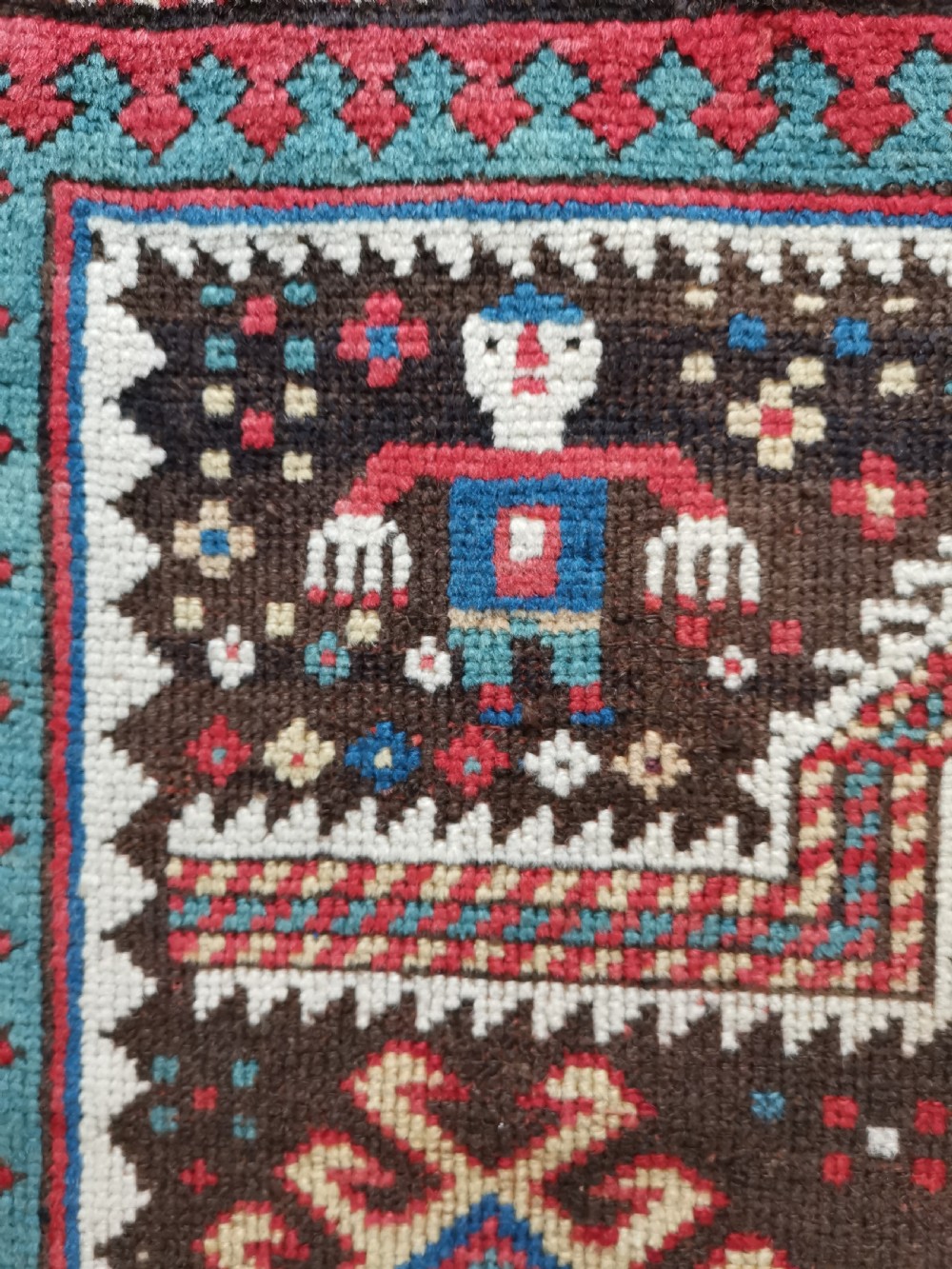 An antique hand-knotted Karabagh prayer rug featuring a dark brown central field with a pointed mihrab arch, geometric diamond motifs, and multi-coloured borders. View III