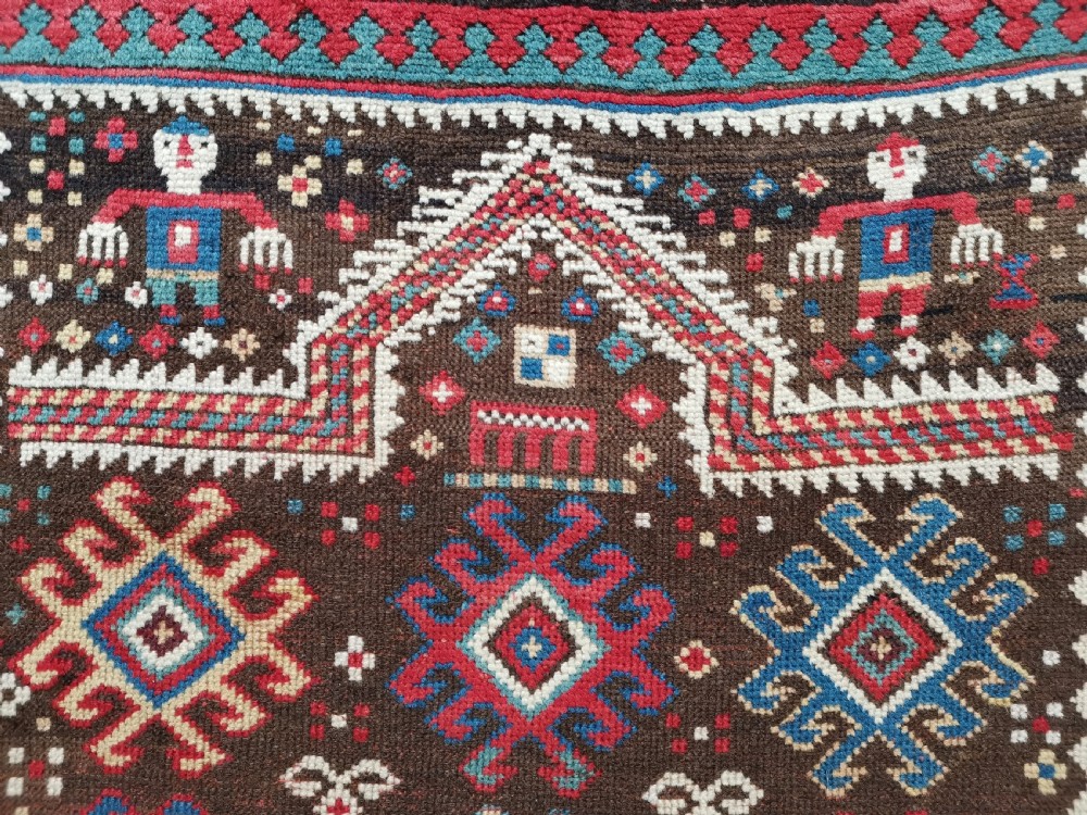 An antique hand-knotted Karabagh prayer rug featuring a dark brown central field with a pointed mihrab arch, geometric diamond motifs, and multi-coloured borders. View V