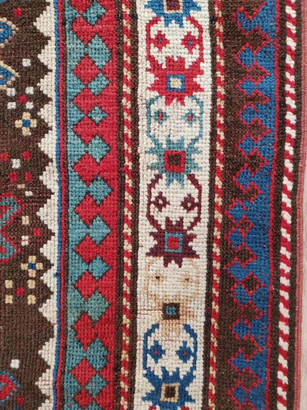 An antique hand-knotted Karabagh prayer rug featuring a dark brown central field with a pointed mihrab arch, geometric diamond motifs, and multi-coloured borders. View VI