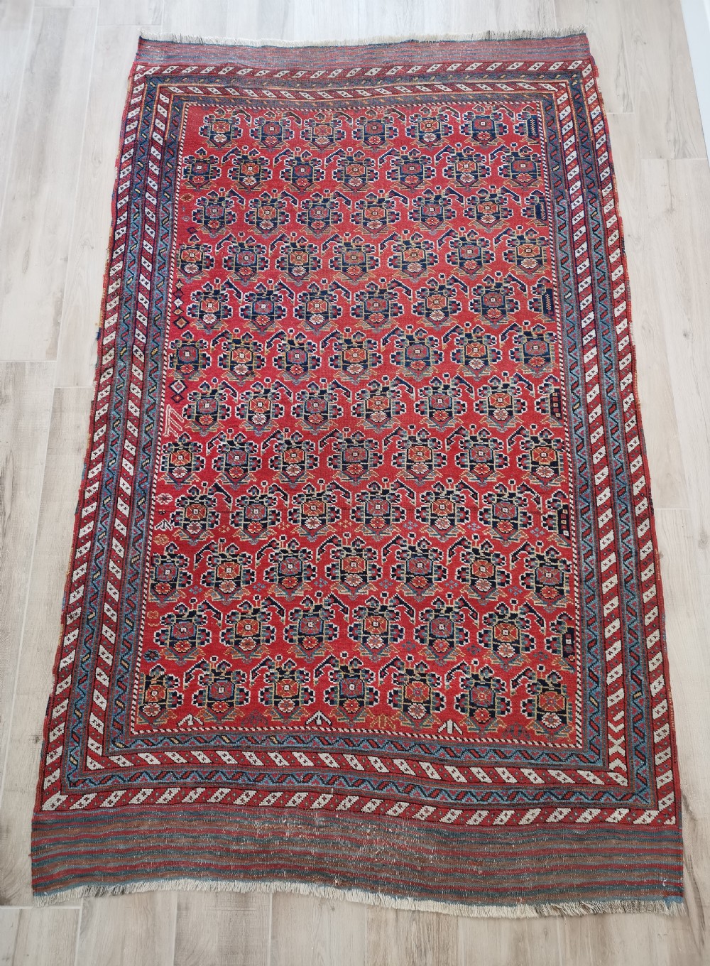 An antique hand-knotted Persian Afshar wool rug featuring a repeating geometric pattern on a deep red field framed by multi-banded borders and flat-woven ends.