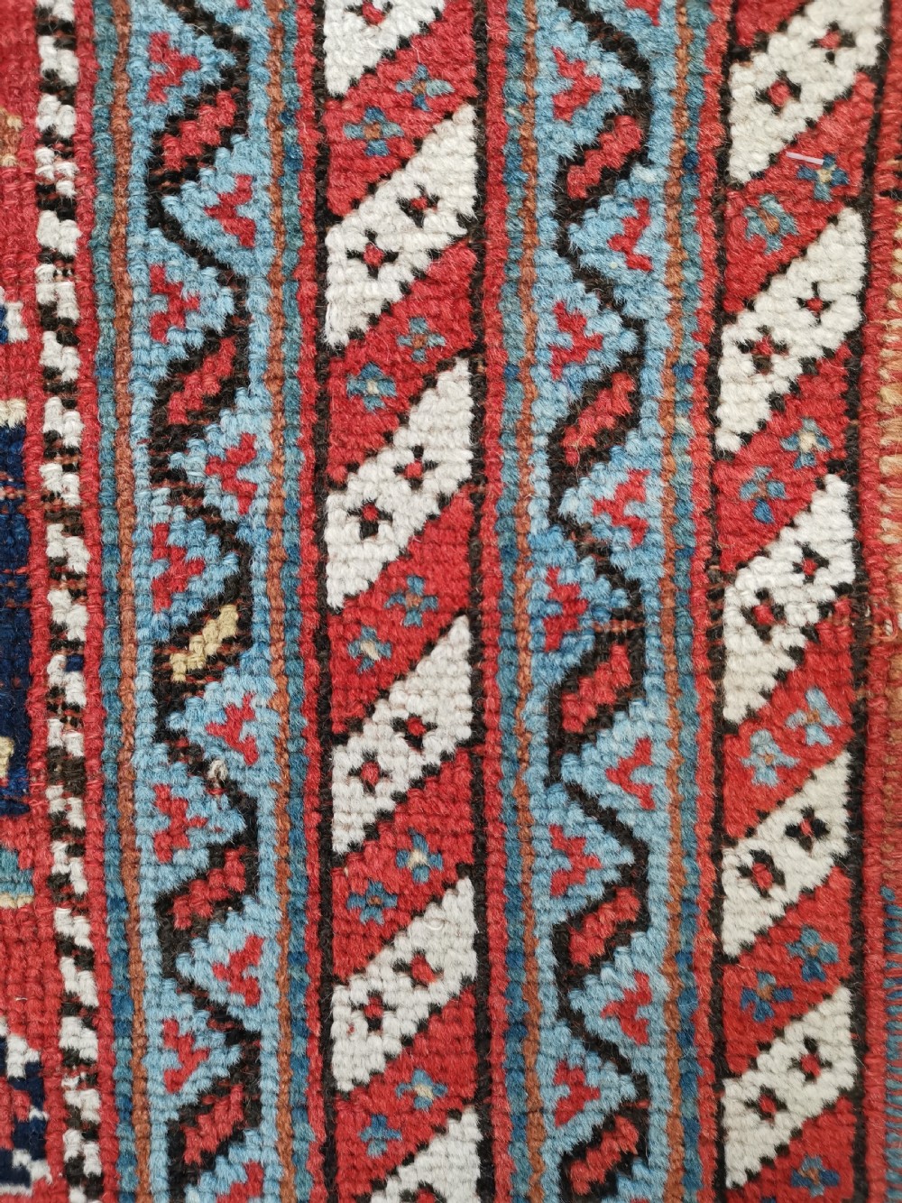 An antique hand-knotted Persian Afshar wool rug featuring a repeating geometric pattern on a deep red field framed by multi-banded borders and flat-woven ends. View III