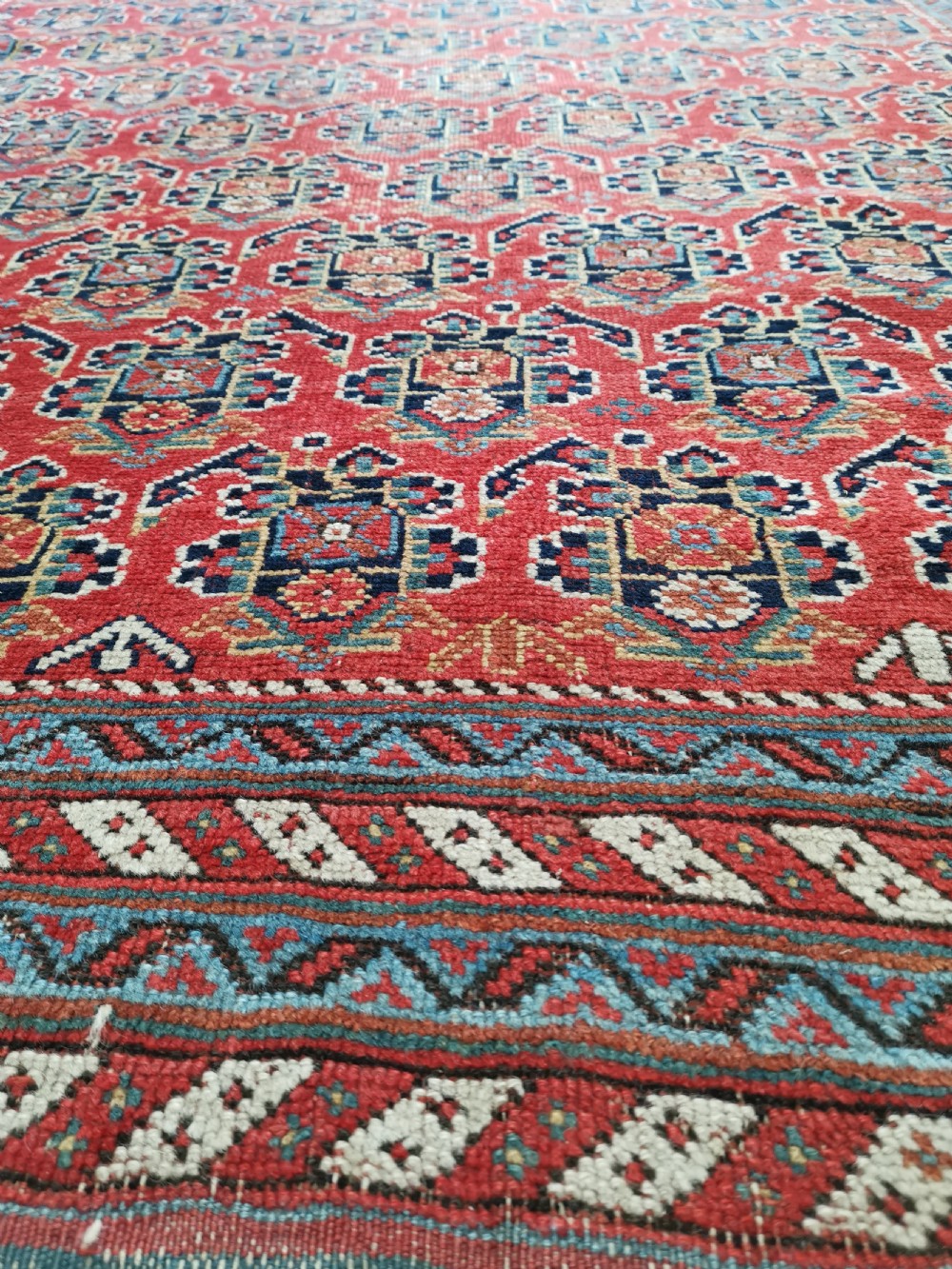 An antique hand-knotted Persian Afshar wool rug featuring a repeating geometric pattern on a deep red field framed by multi-banded borders and flat-woven ends. View IV