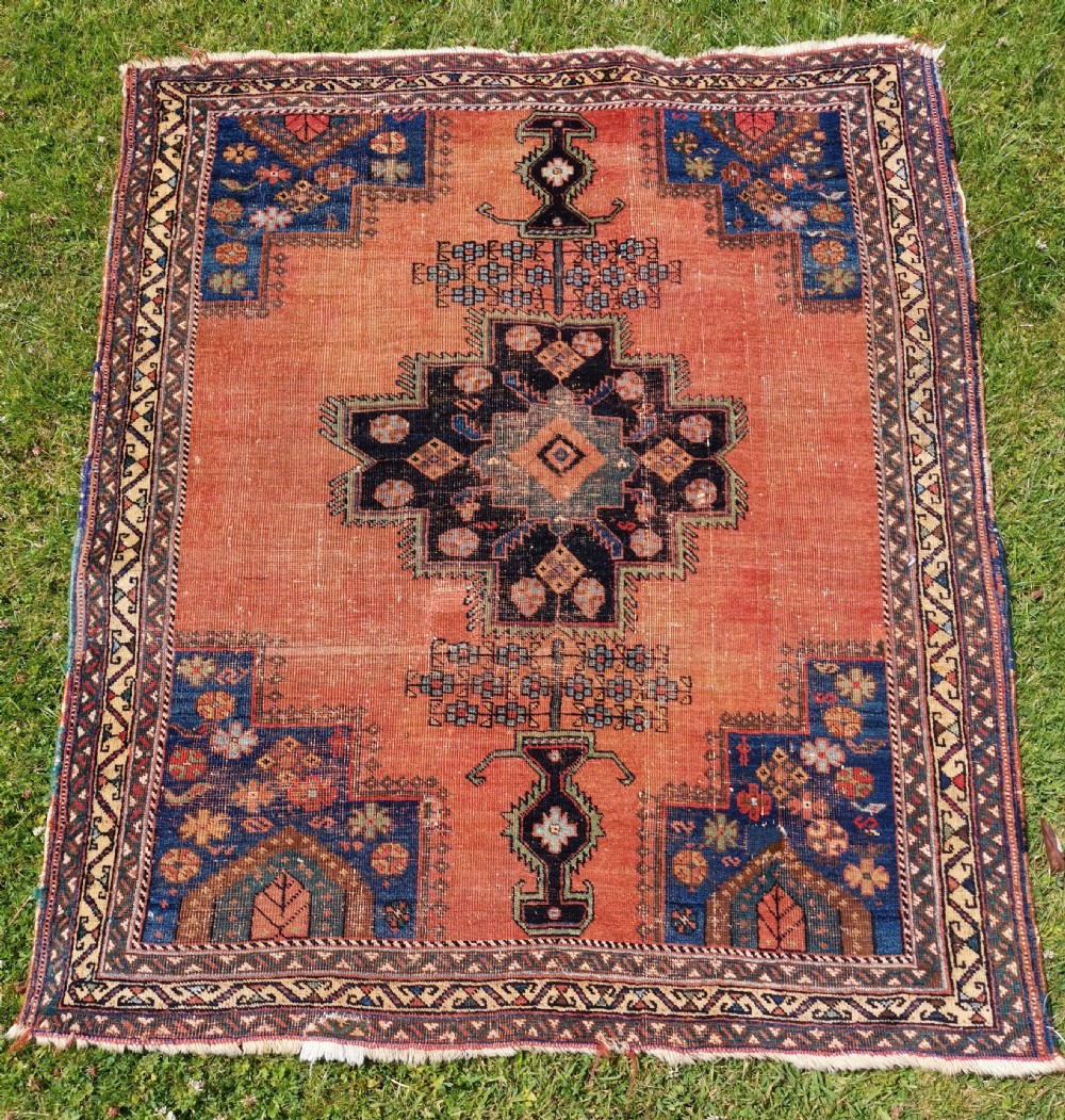 An antique Persian Afshar wool rug featuring a central geometric stepped medallion on a terracotta field with navy blue corner spandrels.