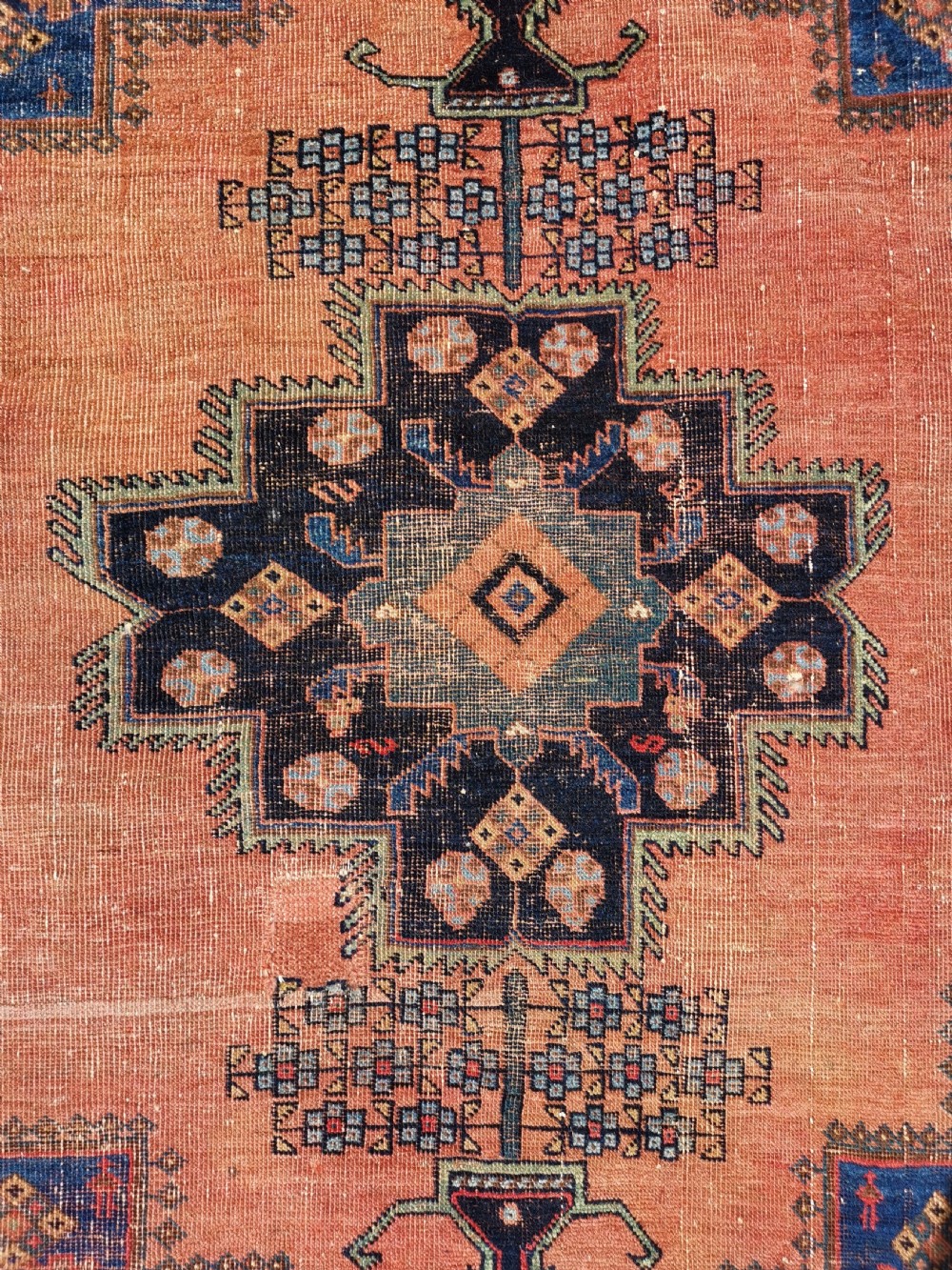 An antique Persian Afshar wool rug featuring a central geometric stepped medallion on a terracotta field with navy blue corner spandrels. View II