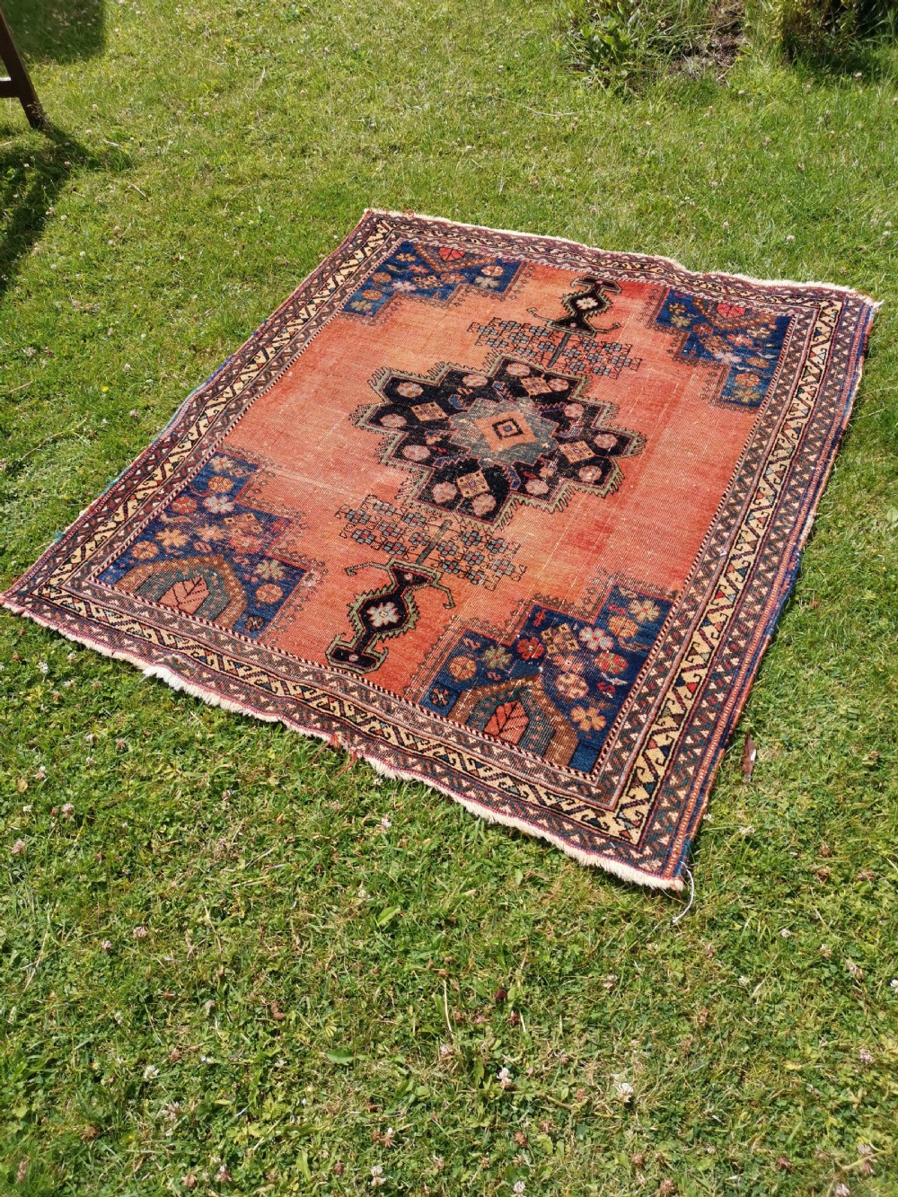 An antique Persian Afshar wool rug featuring a central geometric stepped medallion on a terracotta field with navy blue corner spandrels. View III