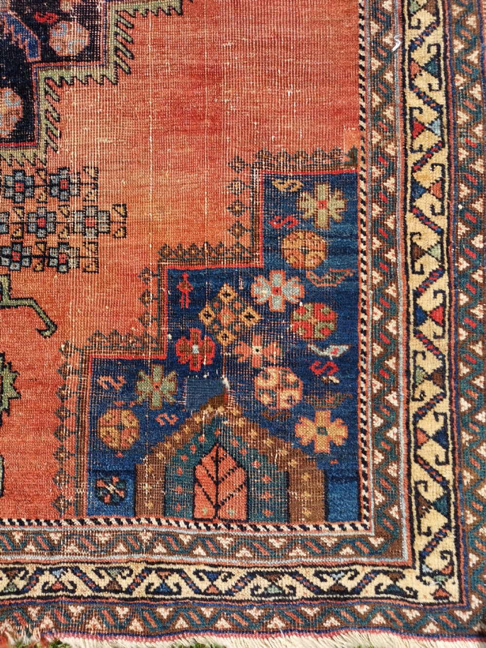 An antique Persian Afshar wool rug featuring a central geometric stepped medallion on a terracotta field with navy blue corner spandrels. View IV