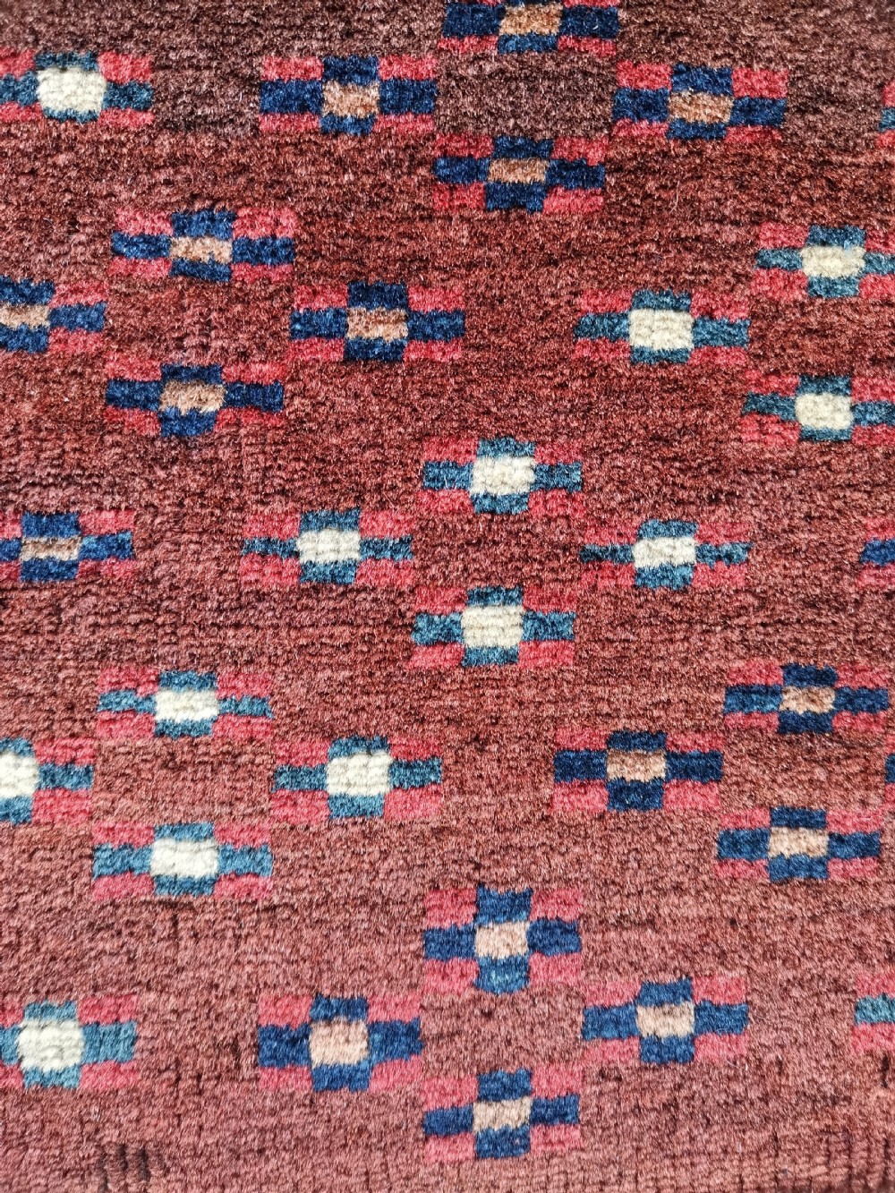 A rectangular hand-knotted wool Yomut chuval featuring rows of geometric guls on a reddish brown field above a patterned lower elem panel. View III