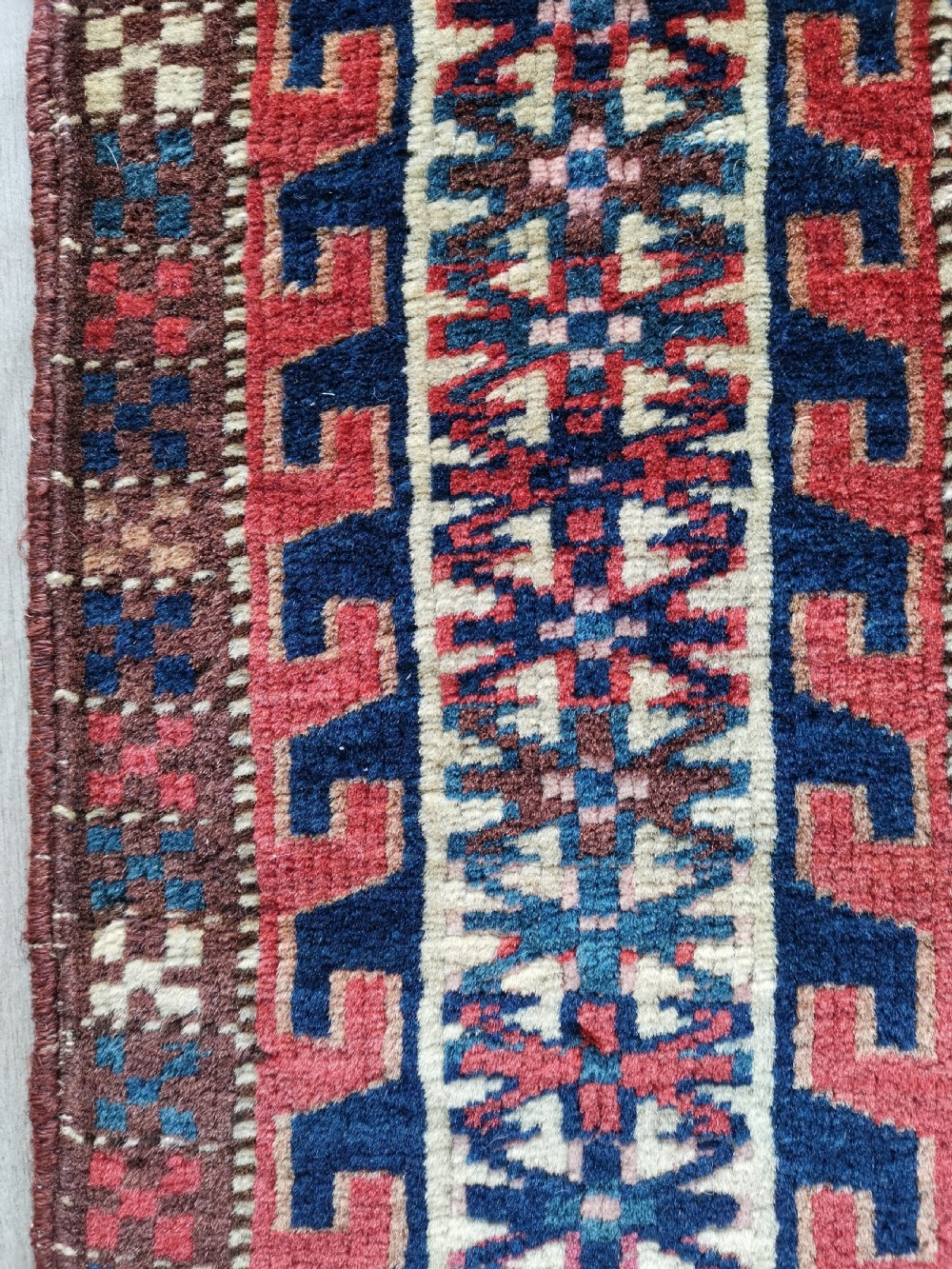 A rectangular hand-knotted wool Yomut chuval featuring rows of geometric guls on a reddish brown field above a patterned lower elem panel. View IV