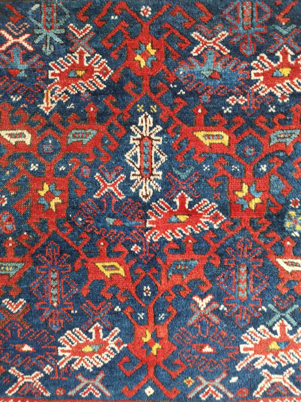 A hand-knotted Anatolian wool rug featuring a deep navy blue central field filled with geometric tribal motifs surrounded by layered madder red and blue borders. View II