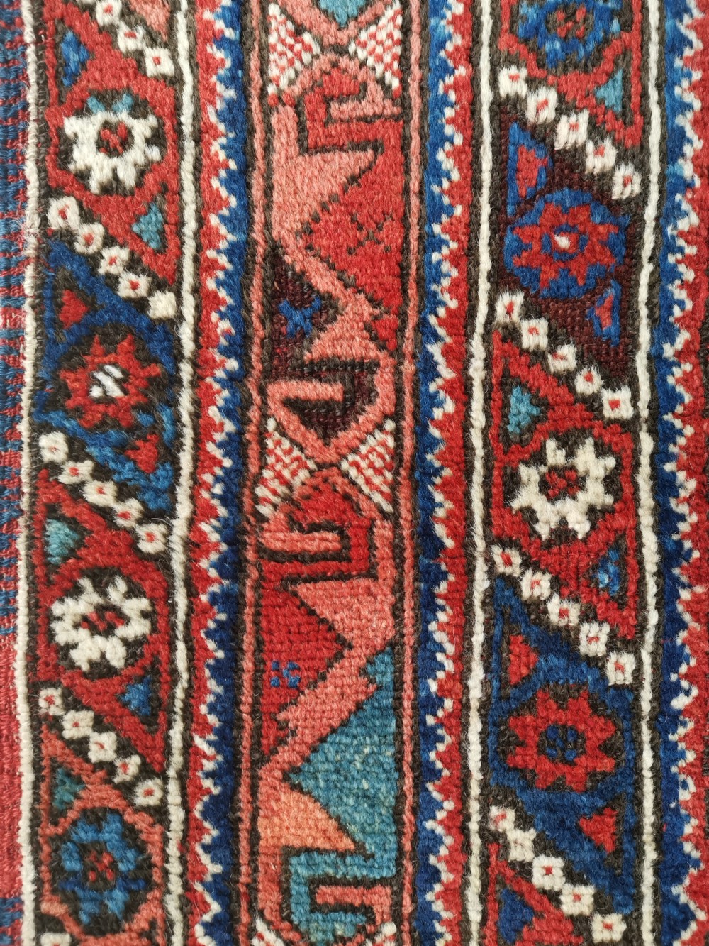 A hand-knotted Anatolian wool rug featuring a deep navy blue central field filled with geometric tribal motifs surrounded by layered madder red and blue borders. View III