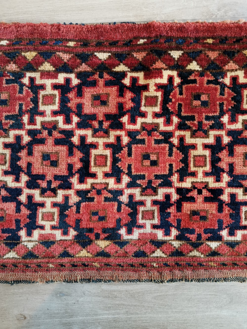 A long, rectangular hand-knotted Ersari torba textile displaying repeating geometric red, navy blue, and cream motifs framed by a narrow patterned border. View II