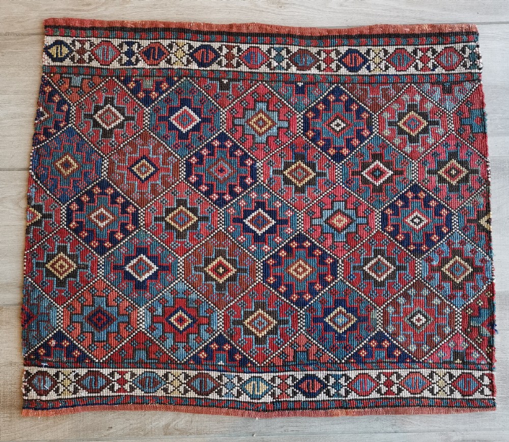 A square antique woven Shahsavan textile panel featuring repeating geometric diamond motifs in terracotta, navy blue, light blue, and ivory.