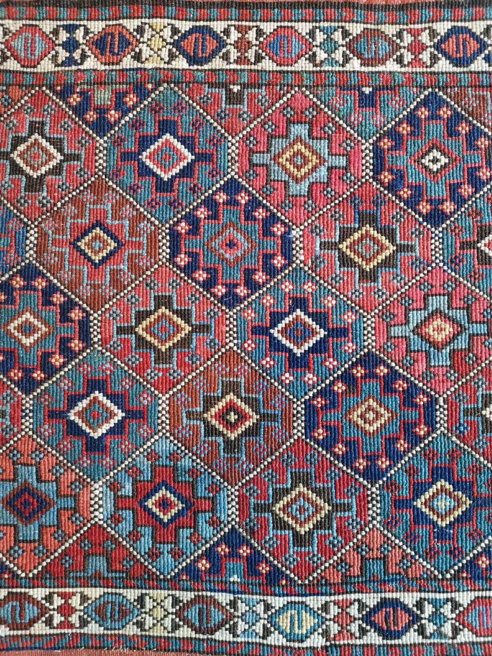 A square antique woven Shahsavan textile panel featuring repeating geometric diamond motifs in terracotta, navy blue, light blue, and ivory. View II