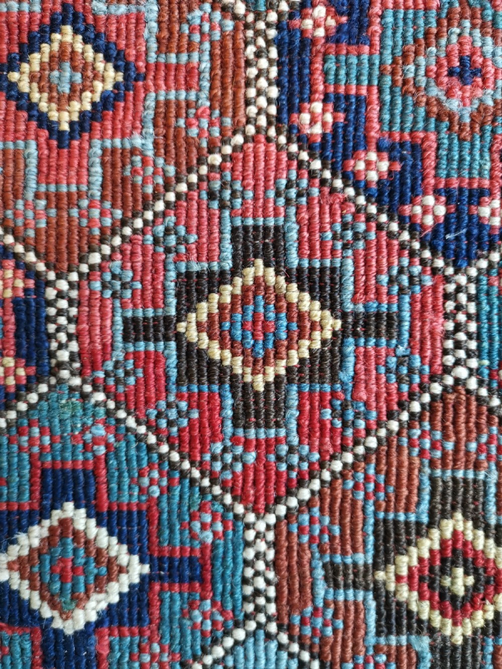 A square antique woven Shahsavan textile panel featuring repeating geometric diamond motifs in terracotta, navy blue, light blue, and ivory. View III