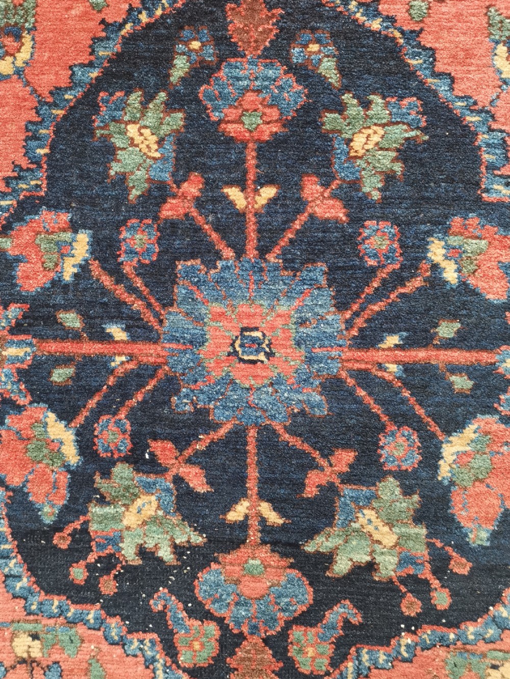 A hand-knotted antique Persian Hamadan rug featuring a central navy blue medallion on a red field framed by patterned borders. View IV